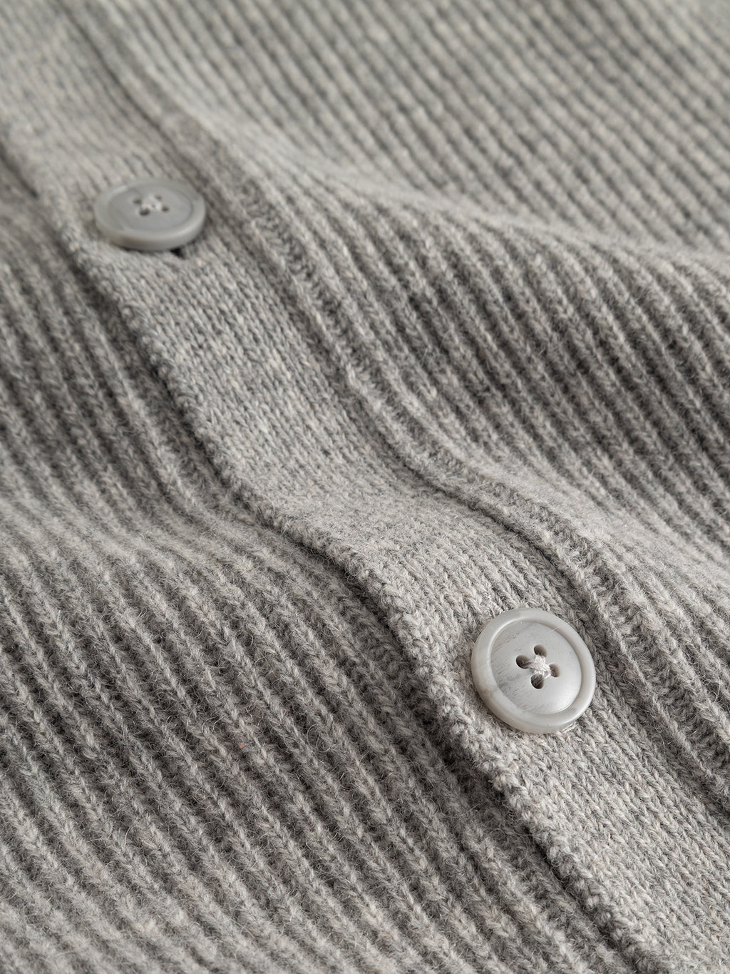 Close-up of the rib-knit gray fabric from the Gabba GABremy Cardi Flash LS Knit - Grey Mel, featuring two light gray buttons sewn on—likely part of this relaxed fit cardigan.