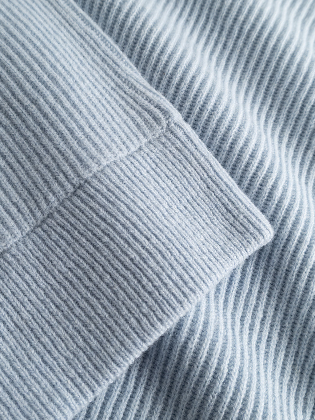 Close-up of the GABremy O-Neck Flash LS Knit in Dusty Blue by Gabba, highlighting the detailed ribbed texture and stitching of the relaxed-fit, 100% wool knit with two overlapping layers visible.