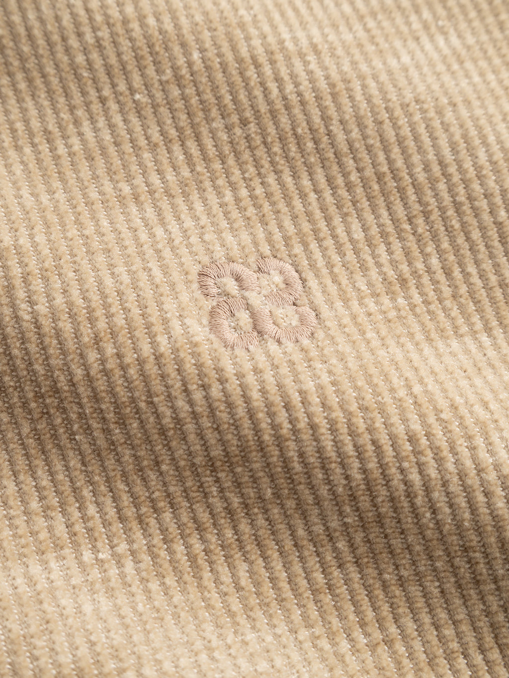 Crafted by Gabba, the GABprimo Fune Hoodie LS Sweat in Sand Crocker features beige jersey corduroy fabric with distinctive vertical ridges and a subtle, light pink embroidered logo centered on the chest. Its regular fit highlights refined stitching and texture details, blending casual comfort with sophisticated style.