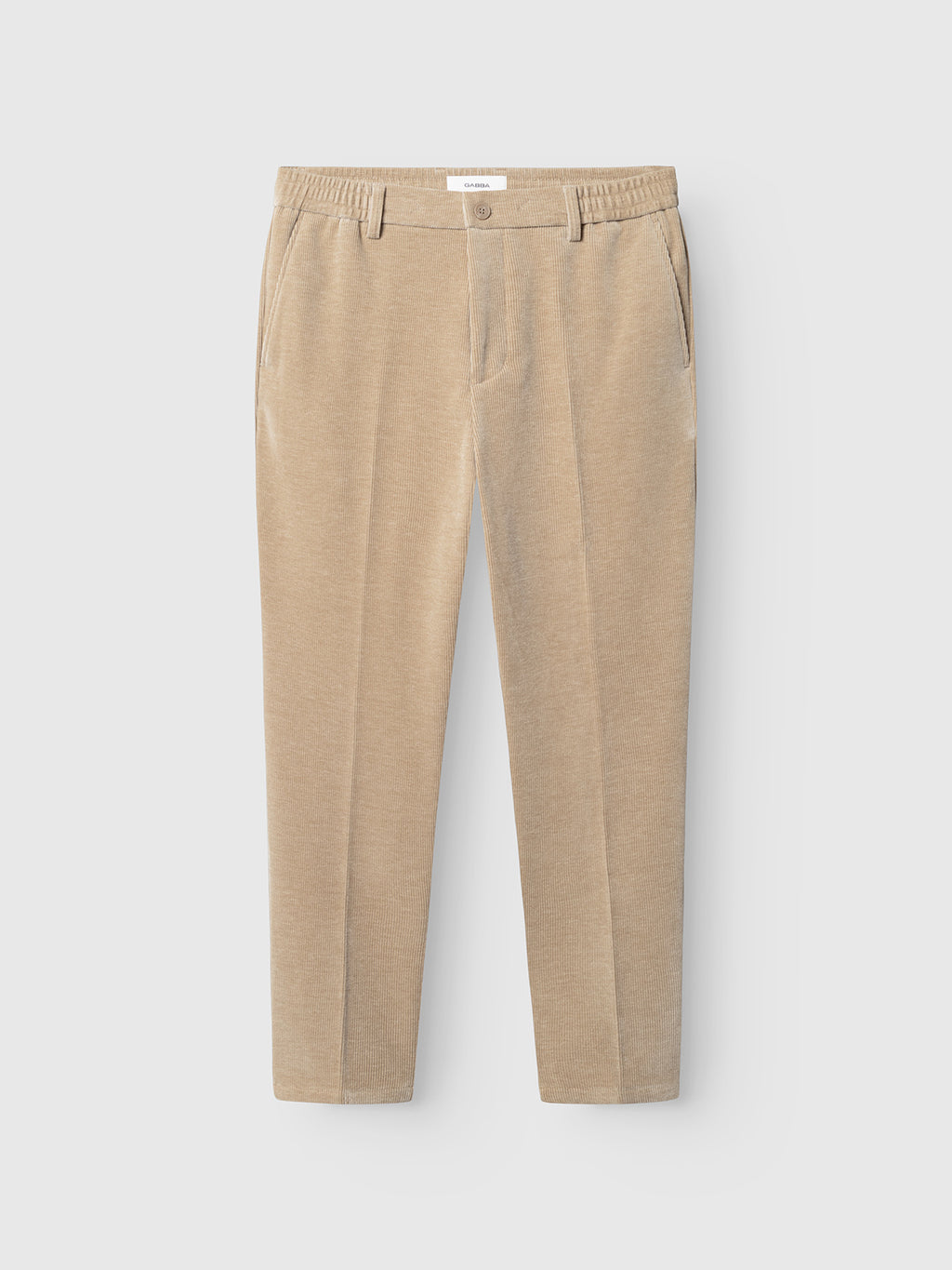 The Gabba GABmonza Cropped Tasca Fune Pant in Sand Crocker features beige jersey corduroy fabric, an elastic waistband, front button closure, side pockets, and a relaxed straight fit with a cropped leg, shown laid flat on a white background.