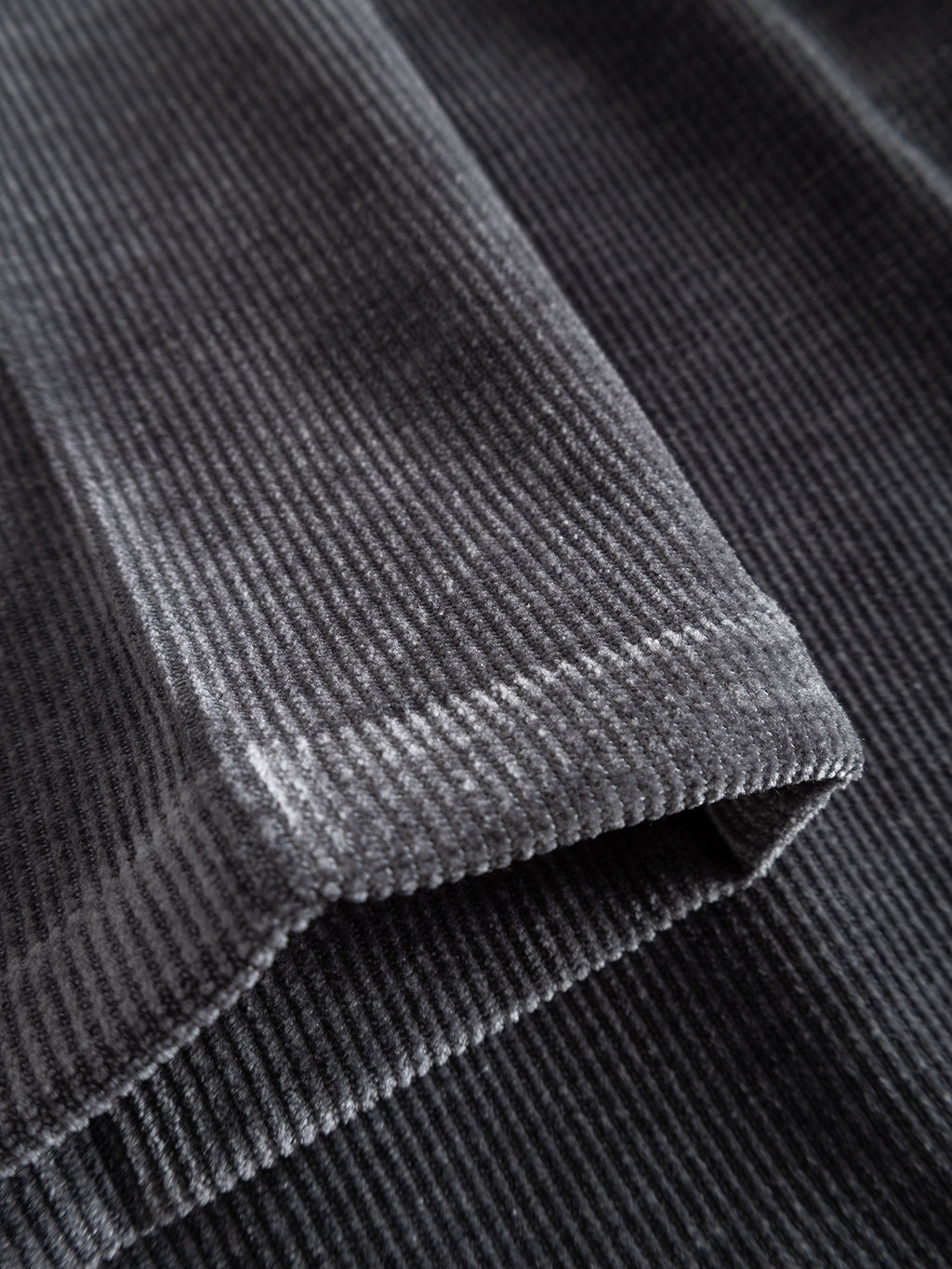 Close-up of folded Turbulence Blue corduroy fabric, highlighting its distinctive parallel ridges and soft texture—characteristic of the premium material featured in the Gabba GABmonza Cropped Tasca Fune Pant, designed with a relaxed straight fit and an elastic waistband.