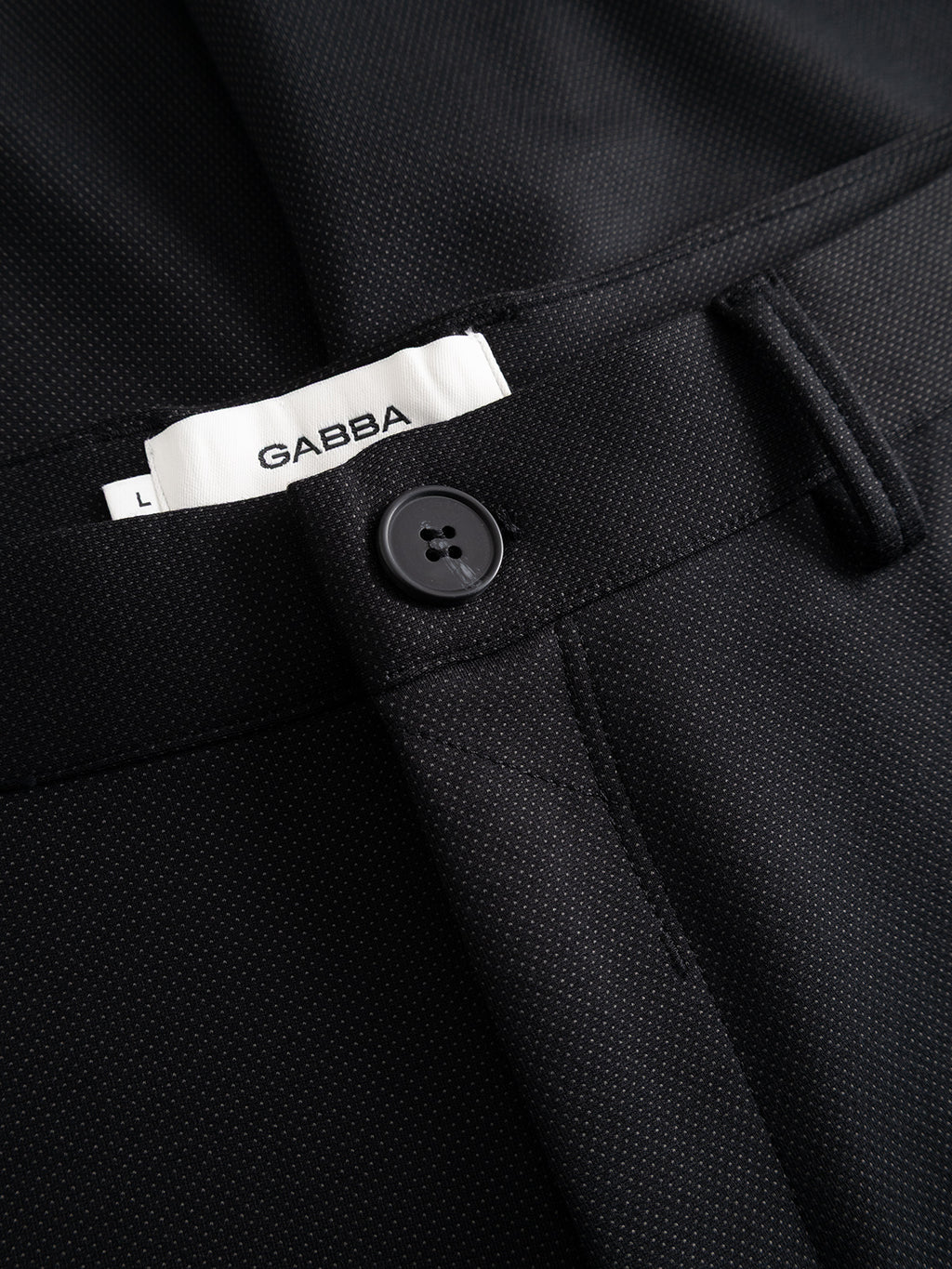 Close-up of the GABpaul Dotty Pant - Meteorite by Gabba, featuring a dark micro-pattern weave, black button fastening, and a visible white Gabba label.