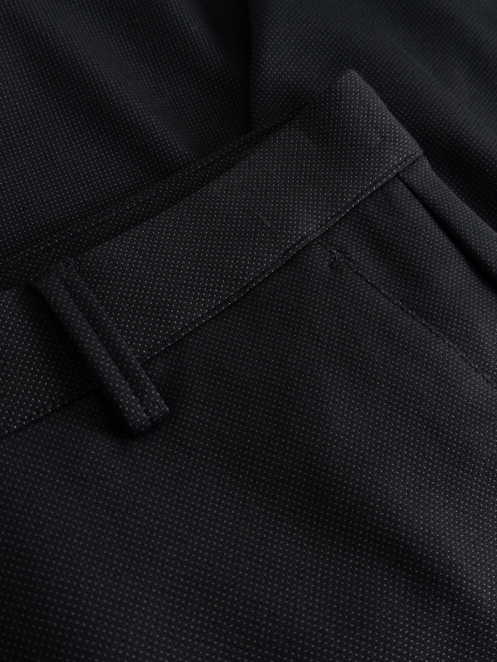 Close-up of the GABpaul Dotty Pant - Meteorite by Gabba, featuring black textured fabric with a subtle micro-pattern weave, highlighting the waistband, belt loop, and top of the pocket on these slim chino fit pants.