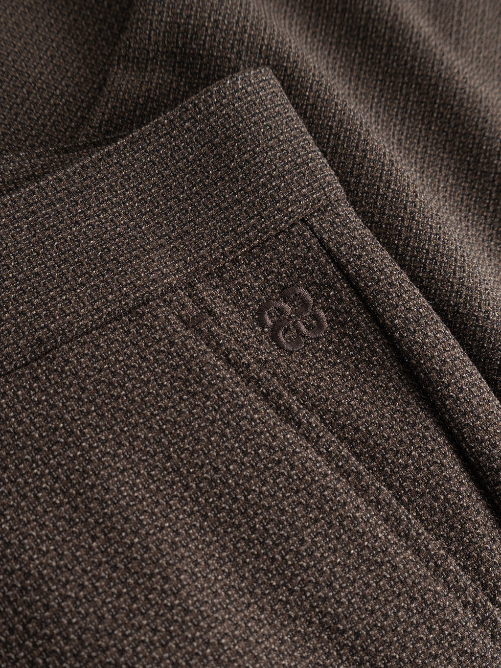 Close-up of the Gabba GABjoe-pas Rubin Pant in Brown Slate, highlighting its textured dobby fabric, subtle embroidered logo near the pocket, detailed stitching, distinctive material pattern, and contemporary tapered fit.