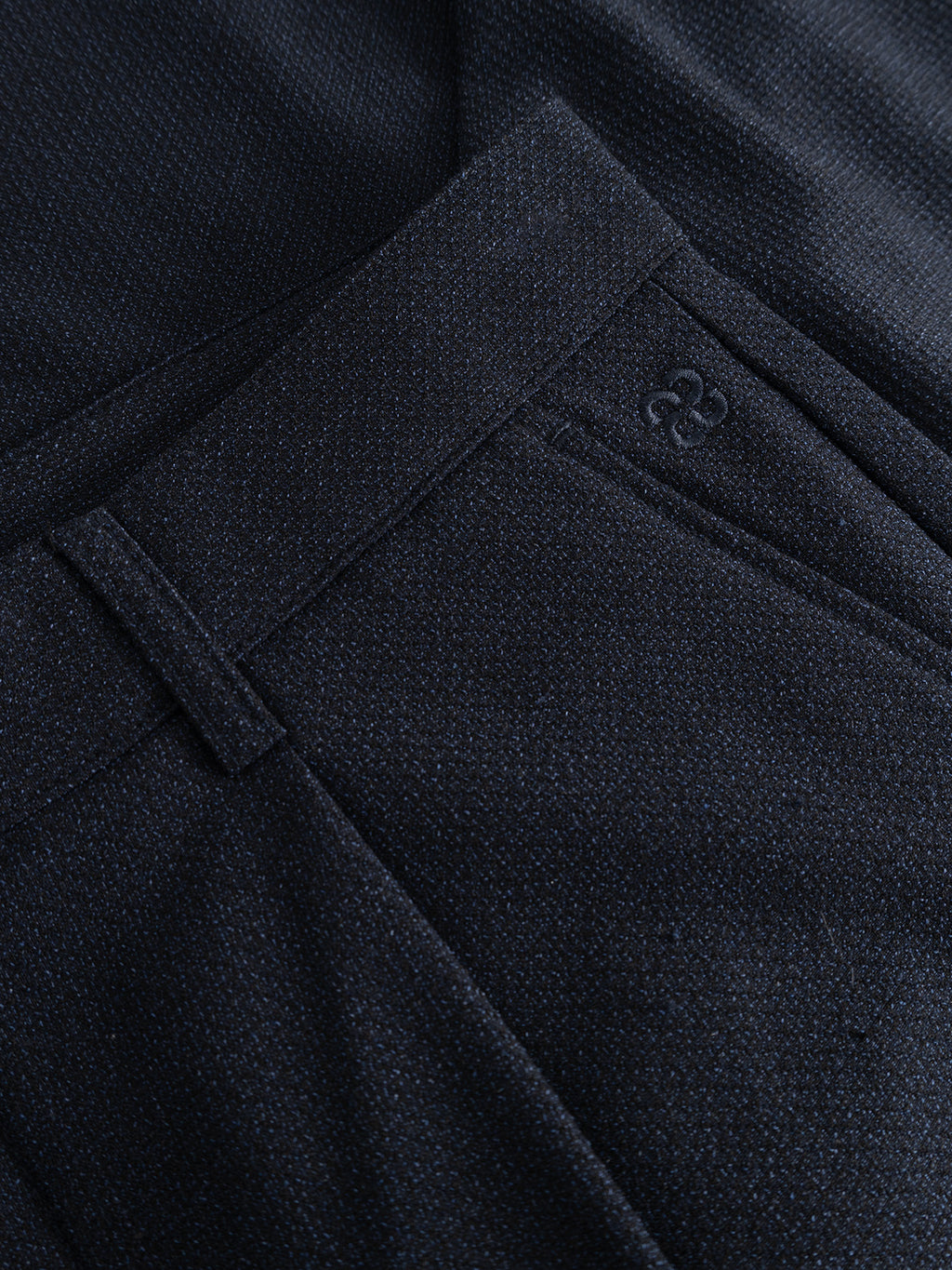Close-up of the GABjoe-pas Rubin Pant - Blue Black by Gabba, tailored from stretch dobby fabric with a textured finish and a subtle embroidered logo above the pocket. The visible waistband and belt loops highlight the pant’s fine stitching details.