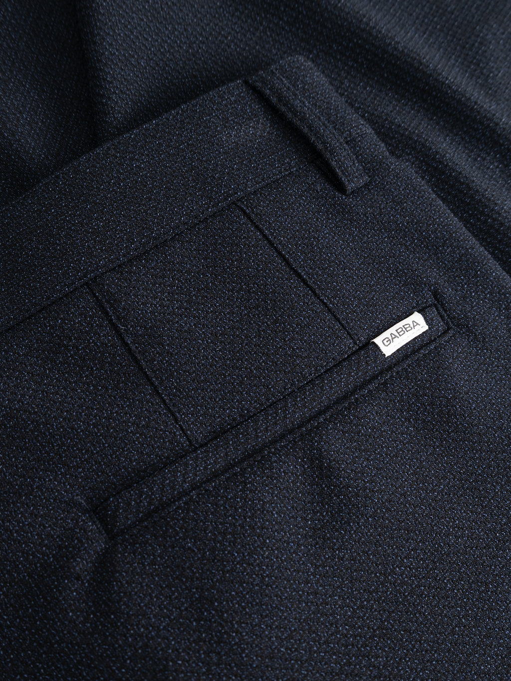 Close-up of a back pocket on Gabba’s GABjoe-pas Rubin Pant in Blue Black, crafted from dark textured stretch dobby fabric, featuring a small white tag labeled OASERA attached to the seam.