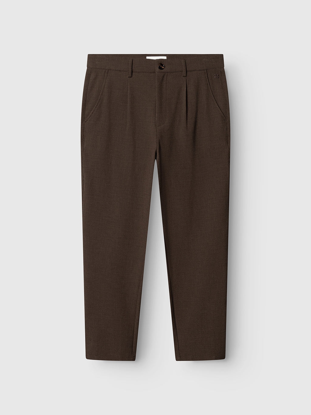 The Gabba GABdavid Rubin Pant in Brown Slate features a dark brown hue and is expertly tailored from stretch dobby fabric. Designed with belt loops, side pockets, a front button, and a zipper fly, these slim-fit chinos are displayed on a plain light grey background. The hem falls just above the ankles, giving the pants a contemporary and modern look.