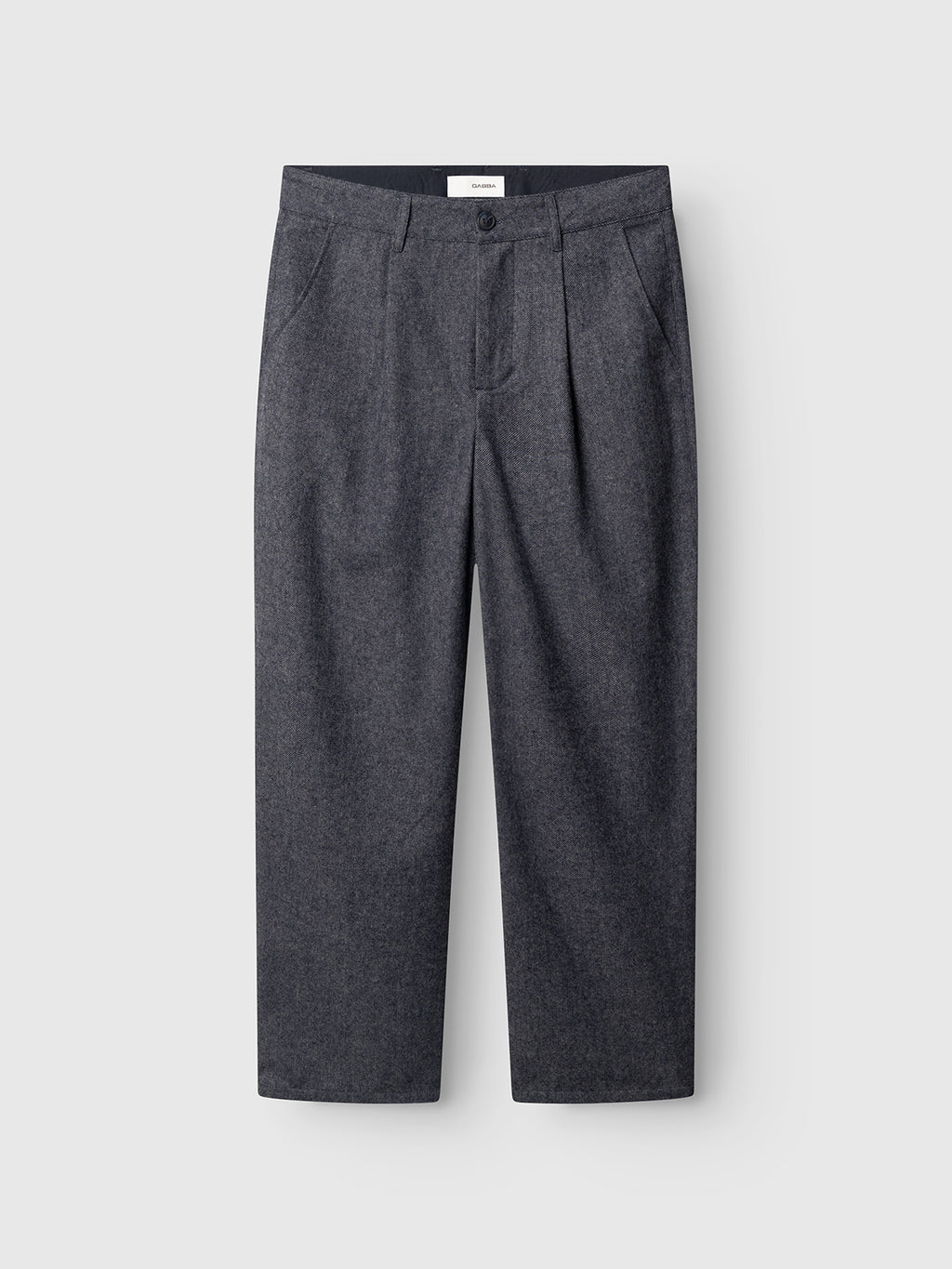 The GABdavid Twilight Pant - Navy by Gabba is displayed against a plain light gray background. These navy wool-blend twill trousers feature front pleats, side pockets, and a buttoned waistband. With their refined, loose tapered fit and clean, minimalist design, these contemporary chinos are perfect for modern wardrobes.