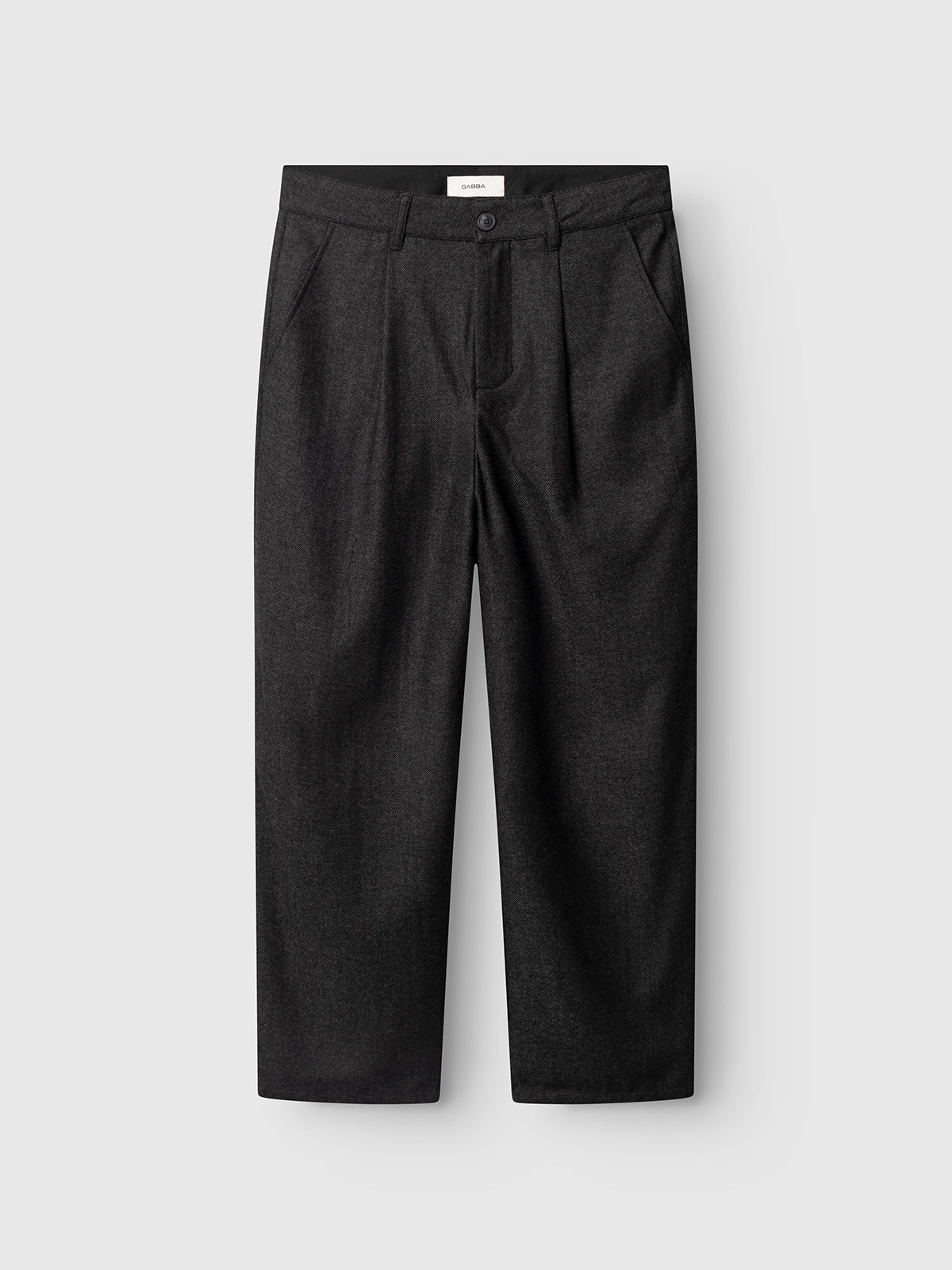 The GABdavid Twilight Pant - Dark Grey by Gabba features a loose tapered fit crafted from a dark gray wool-blend twill, designed with a button and zip closure, belt loops, two side pockets, and two back pockets. Displayed flat against a light gray background, these trousers offer a modern reinterpretation of the contemporary chino.