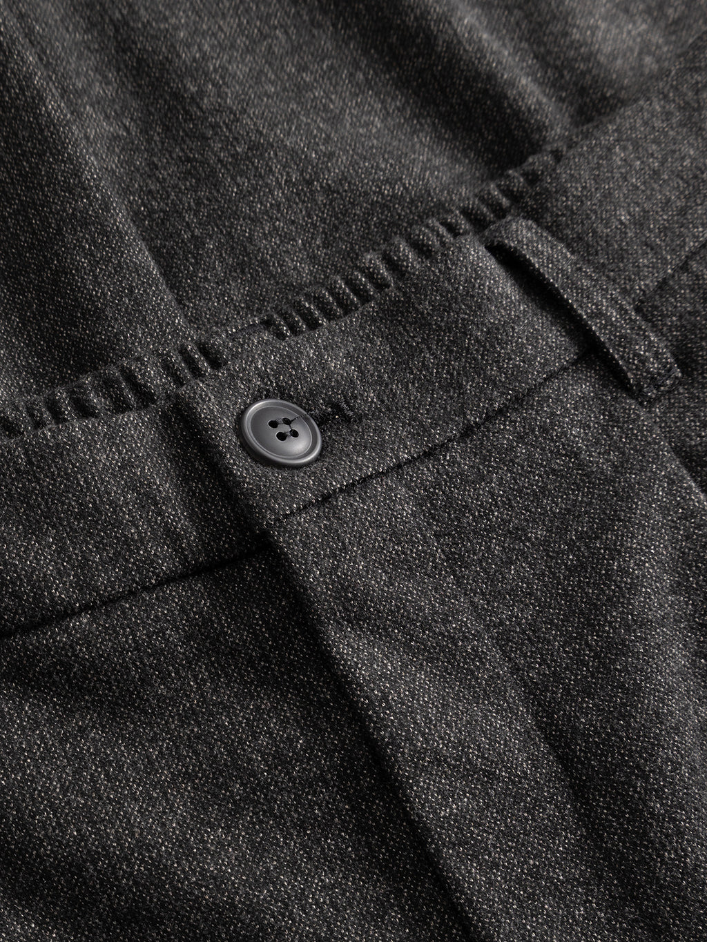 Close-up of the Gabba GABnapoli 19 Zaffe GRS Pant in dark grey, featuring textured fabric with a black button, belt loop, and visible stitching near the waistband. Crafted from soft stretch material for added comfort, these regular straight fit trousers offer a sophisticated wool-look finish.