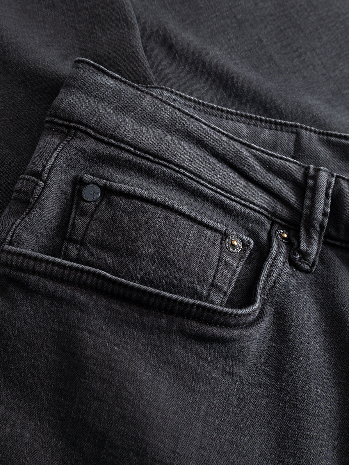 Close-up of the back pocket and waistband of the Gabba GABjones Hesky Jeans in black denim, highlighting meticulous stitching details and a small rivet near the pocket. Crafted from high-stretch denim, these jeans deliver a comfortable slim straight fit while preserving classic style elements.