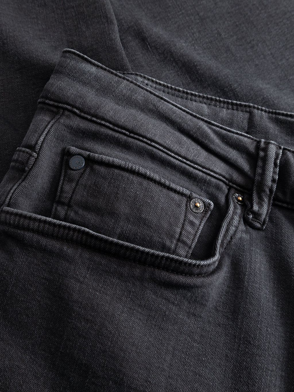 Close-up of the back pocket and waistband of the Gabba GABjones Hesky Jeans in black denim, highlighting meticulous stitching details and a small rivet near the pocket. Crafted from high-stretch denim, these jeans deliver a comfortable slim straight fit while preserving classic style elements.