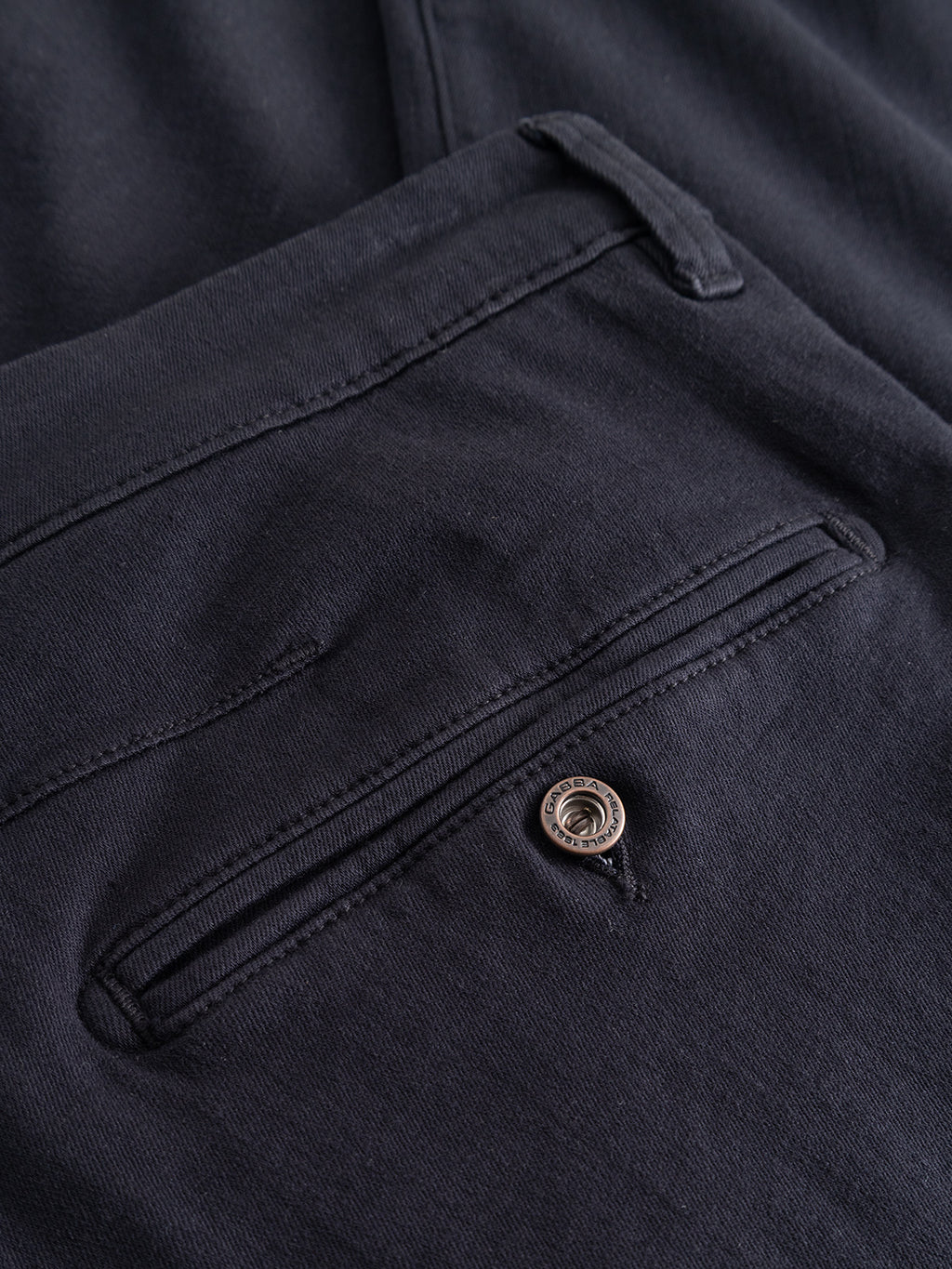 Close-up of the back pocket on the Gabba GABpaul Hesky Pant in navy, featuring a single black button and stitched detailing around the pocket opening. Crafted from high-stretch garment-dyed fabric, these versatile chinos offer both comfort and style.