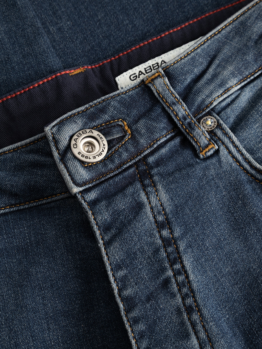 Close-up of the Gabba GABjones2 Nham RS2113 Jeans in dark blue denim, featuring visible stitching, a silver button, and a branded label on the waistband. Made from performance stretch denim in a dark blue wash, these slim straight fit jeans are shown slightly open to reveal the inner waistband with distinctive red stitching detail.