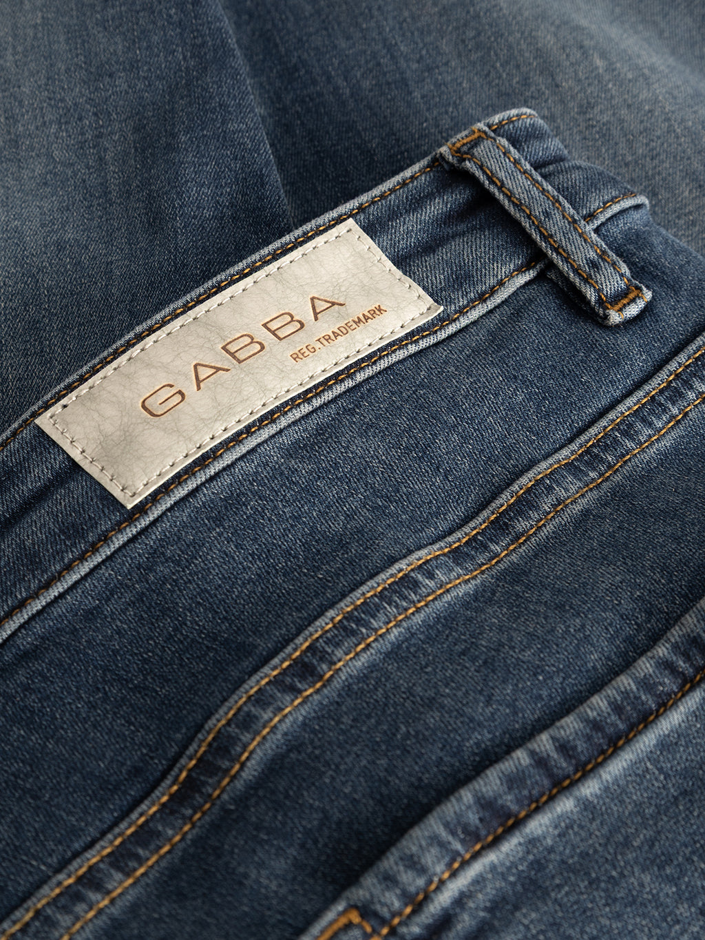 Close-up of Gabba GABjones2 Nham RS2113 Jeans in dark blue denim, featuring a white label reading GABBA REG TRADEMARK stitched above the back pocket, and highlighting the detailed stitching and premium performance stretch denim fabric.