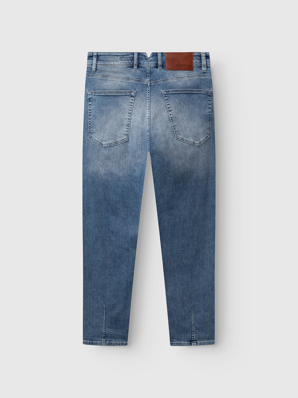 A pair of Gabba GABalex Cropped Nham RS2112 Jeans in mid blue denim, showcased from the back with two rear pockets, stitched detailing, belt loops, and a brown leather patch on the waistband. Made from ISKO stretch denim for performance comfort, these jeans feature a relaxed tapered fit that blends modern style with everyday ease.