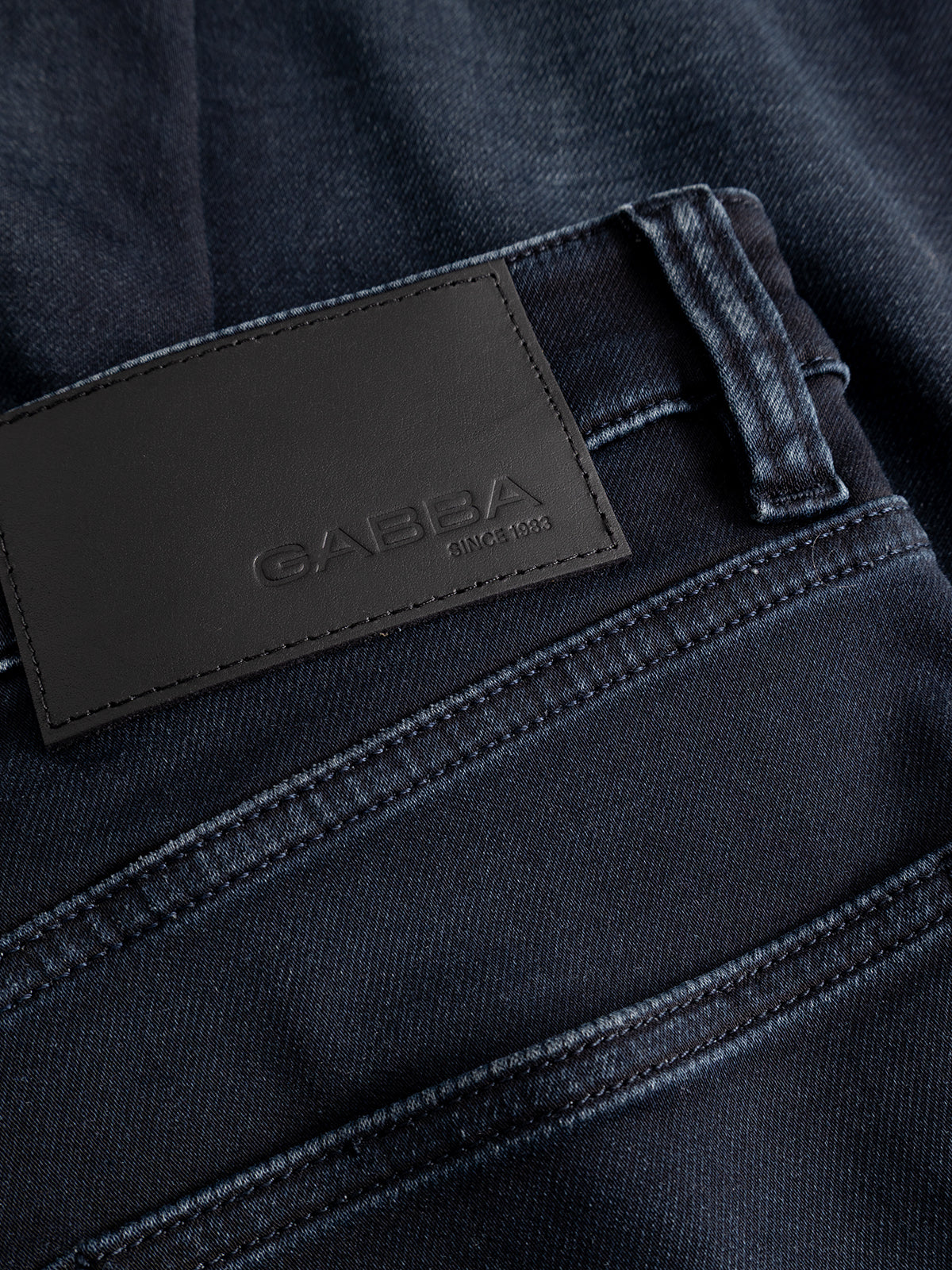 Close-up of the GABalex Cropped Torino RS2106 Jeans in dark blue denim, highlighting the waistband and a black leather patch embossed with the Gabba brand name and “since 1983.”.
