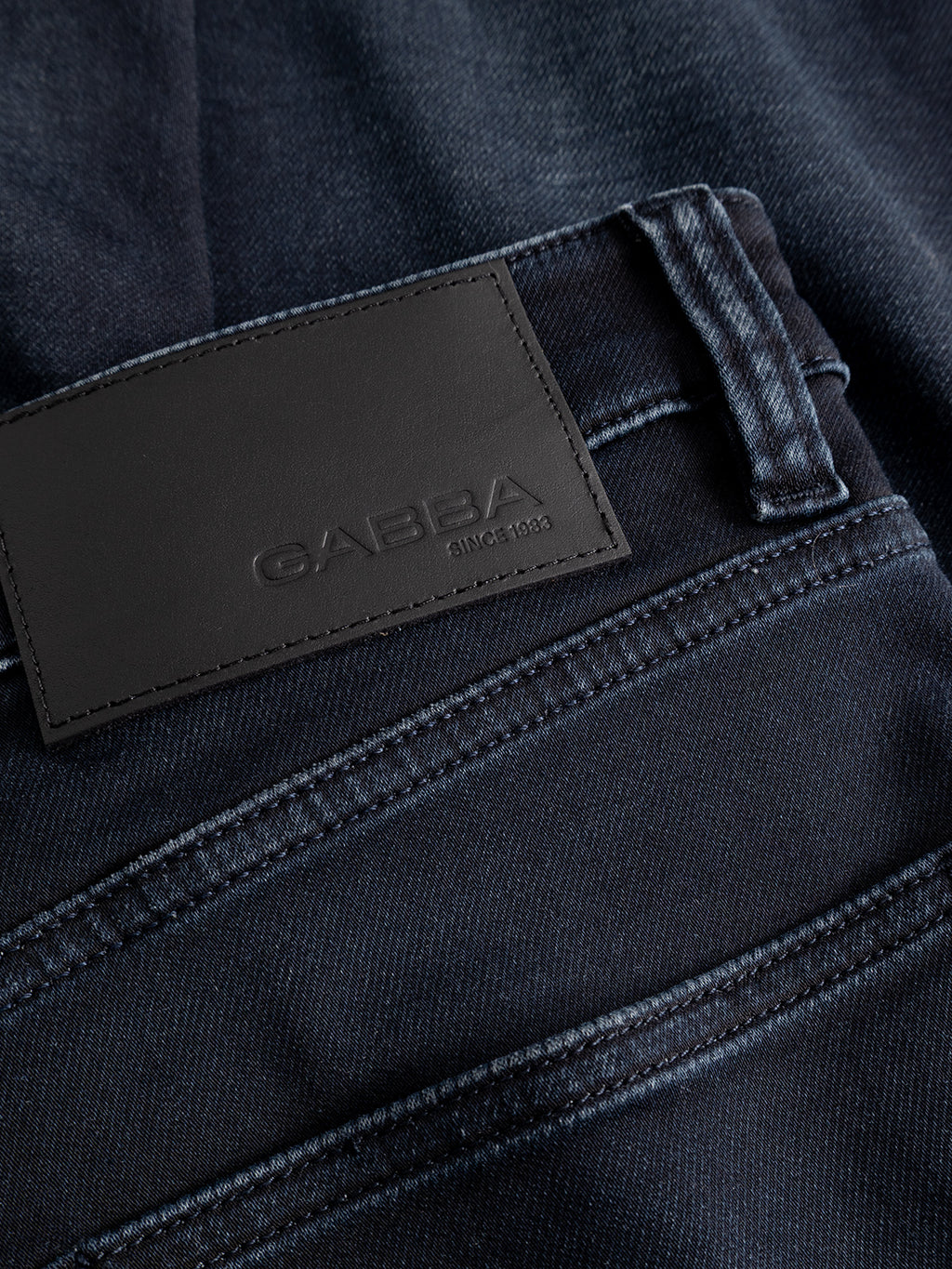 Close-up of the GABalex Cropped Torino RS2106 Jeans in dark blue denim, highlighting the waistband and a black leather patch embossed with the Gabba brand name and “since 1983.”.