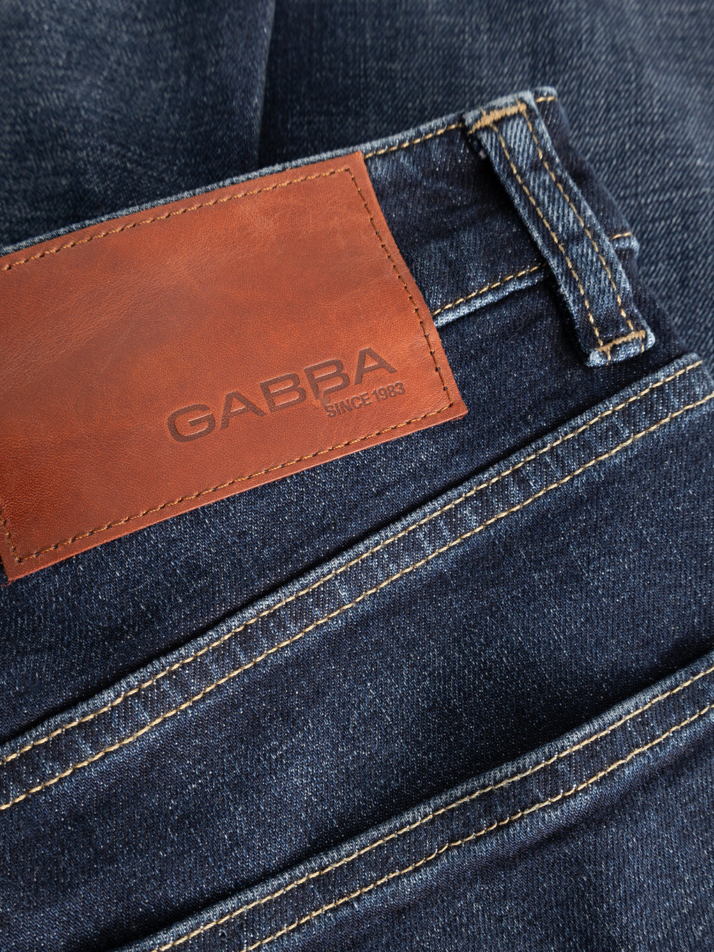 Close-up of the GABalex Cropped Cros RS2108 Jeans RCS in dark blue denim showing a brown leather patch with the Gabba brand name and “Since 1983,” along with visible belt loops and detailed stitching. The cross-hatch texture of the denim and relaxed tapered fit enhance its contemporary appeal.