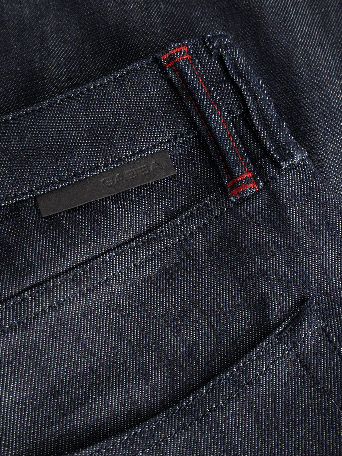 Close-up of the premium Gabba GABcarl Anark Stone Raw Jeans in dark blue denim, showcasing the pocket’s detailed stitching, including a vertical bar of red thread near the seam and a small black label above the pocket. The loose tapered fit is subtly evident from the silhouette.