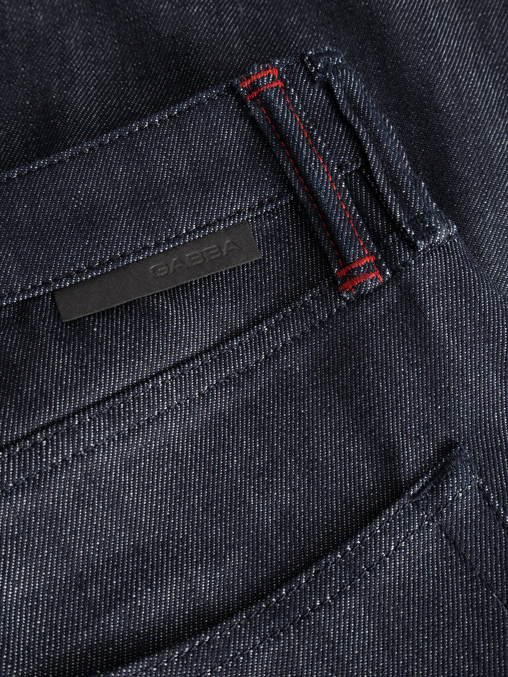Close-up of the premium Gabba GABcarl Anark Stone Raw Jeans in dark blue denim, showcasing the pocket’s detailed stitching, including a vertical bar of red thread near the seam and a small black label above the pocket. The loose tapered fit is subtly evident from the silhouette.