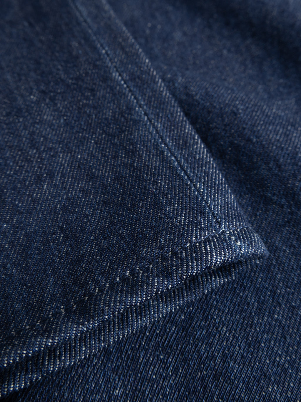 Close-up of dark blue rigid indigo denim fabric from the GABnoah Tona Rinse Jeans by Gabba, featuring visible stitching and texture, with a folded corner detail highlighting the craftsmanship of these loose straight fit jeans made from an organic cotton blend.