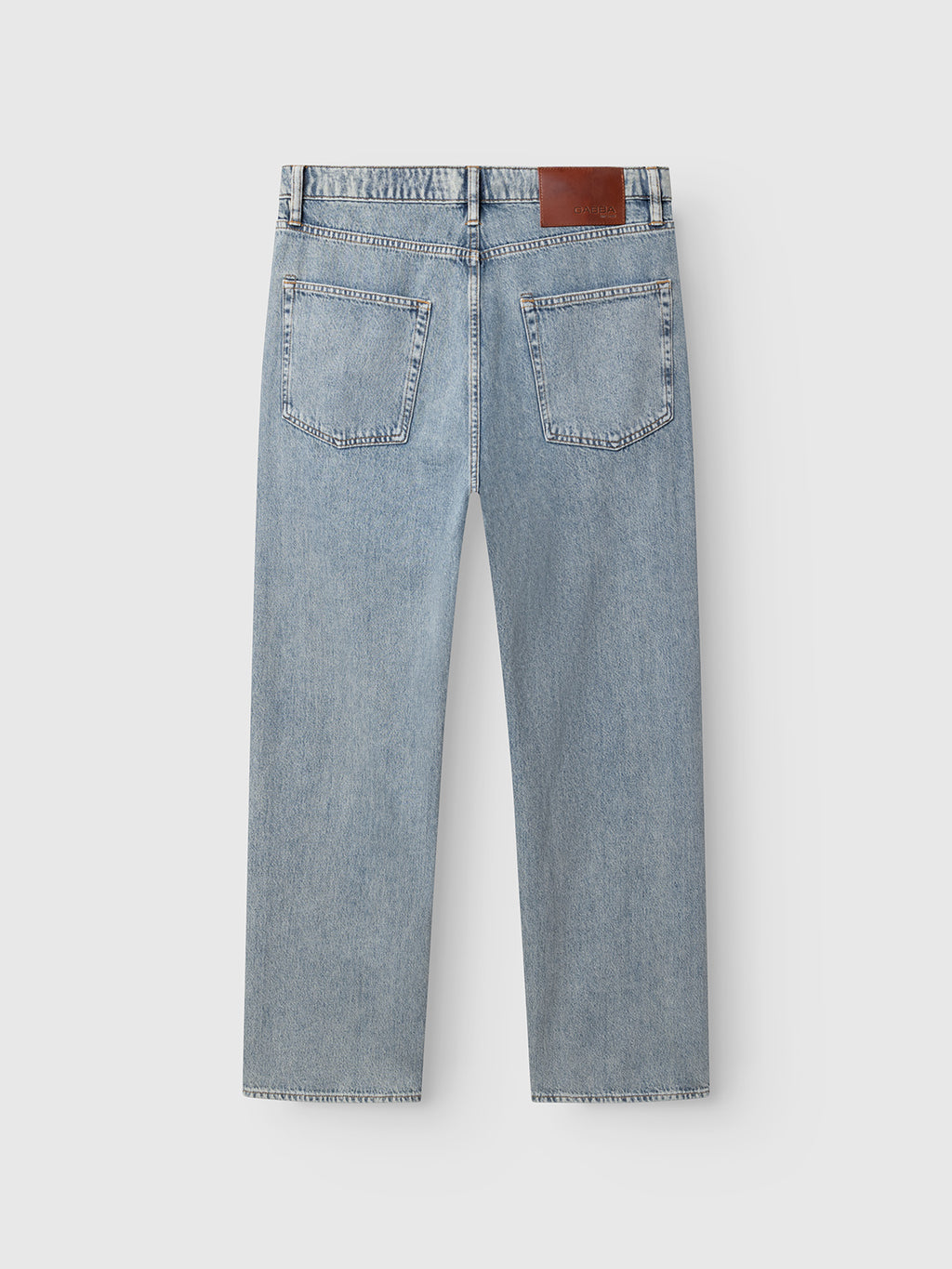 The GABnoah Tona RS2100 Jeans by Gabba are shown from the back in mid blue denim, featuring two rear pockets, straight legs, and a brown leather patch on the waistband. Made from organic cotton for lasting comfort, these loose straight fit jeans are laid flat on a plain white background.