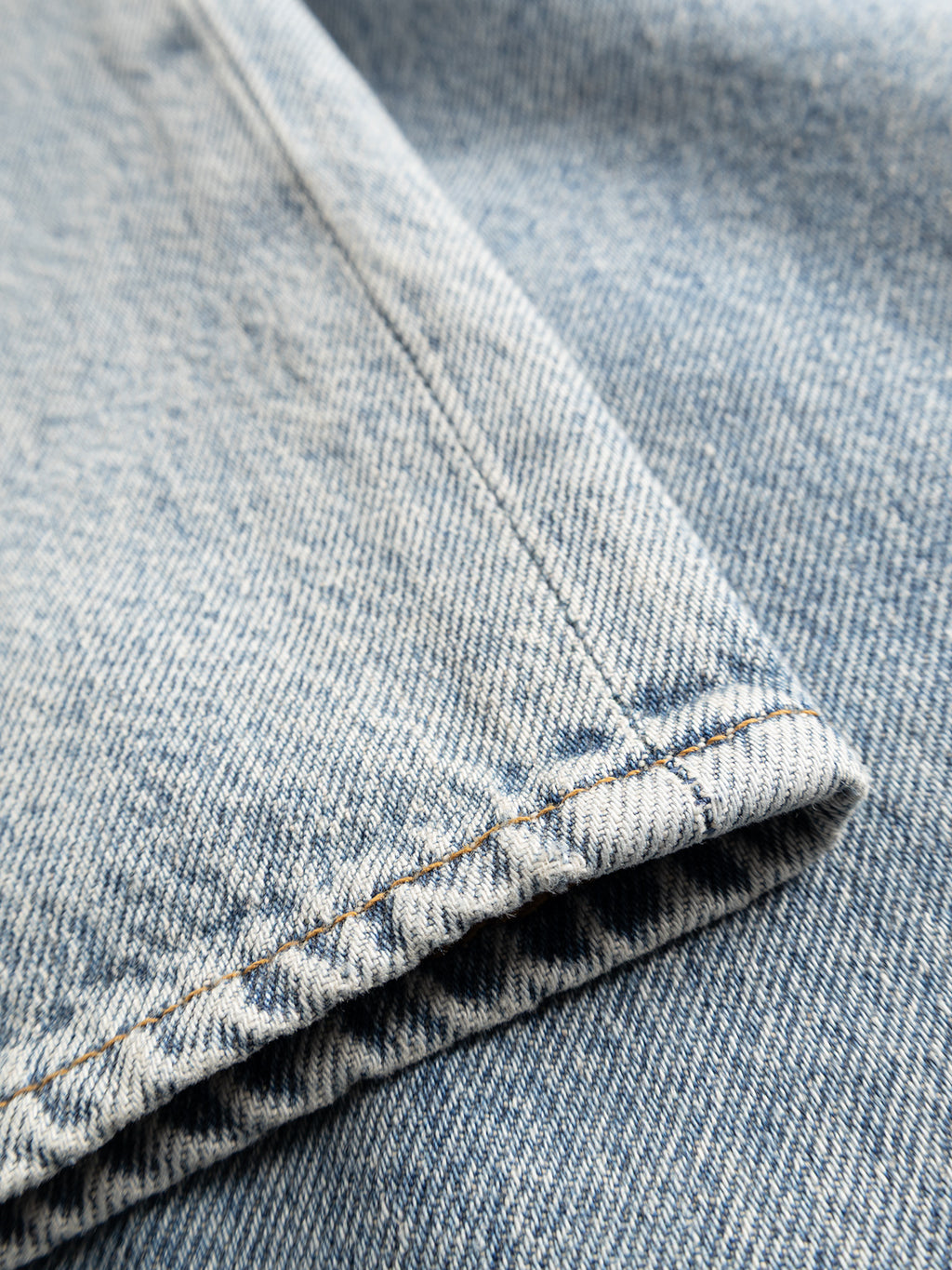 Close-up of the GABnoah Tona RS2100 Jeans by Gabba in mid blue denim, showcasing the seam and hem to emphasize the textured fabric, precise stitching, and subtle faded wash. Made from organic cotton, these jeans highlight quality craftsmanship and sustainability while preserving a timeless denim aesthetic.