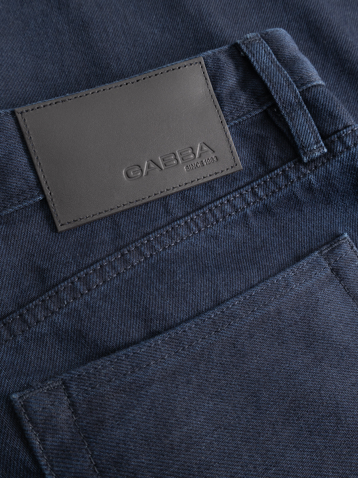 Close-up of a pair of GABsenna Denia Rinse Jeans in dark blue denim from Gabba, designed in a loose tapered fit and featuring a gray leather patch with the brand name “Gabba Since 1983” above the back pocket.
