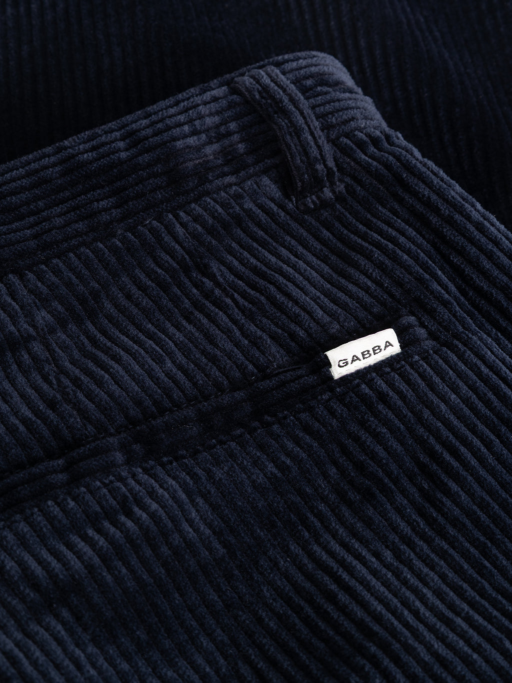 Close-up of the dark navy GABjoe Nopleats Ibre Pant by Gabba, highlighting the stretch corduroy texture and a small white Gabba tag near the waistband.