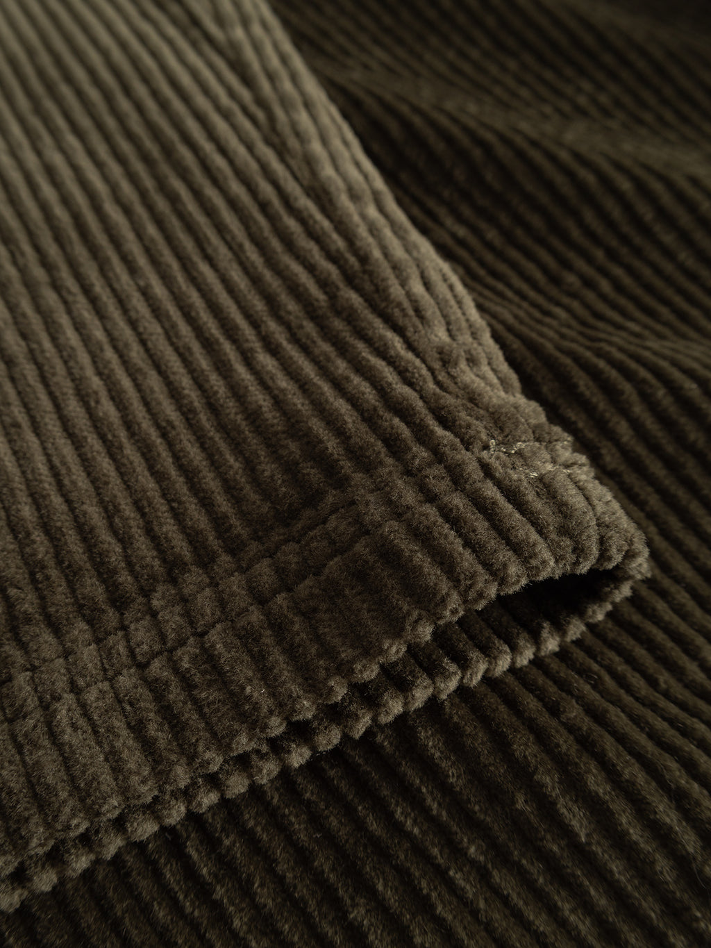 Close-up of ‘Forest Night’ stretch corduroy fabric from the Gabba GABjoe Nopleats Ibre Pant, showing a textured, ribbed pattern and visible stitching along the folded edge, highlighting its classic chino construction.