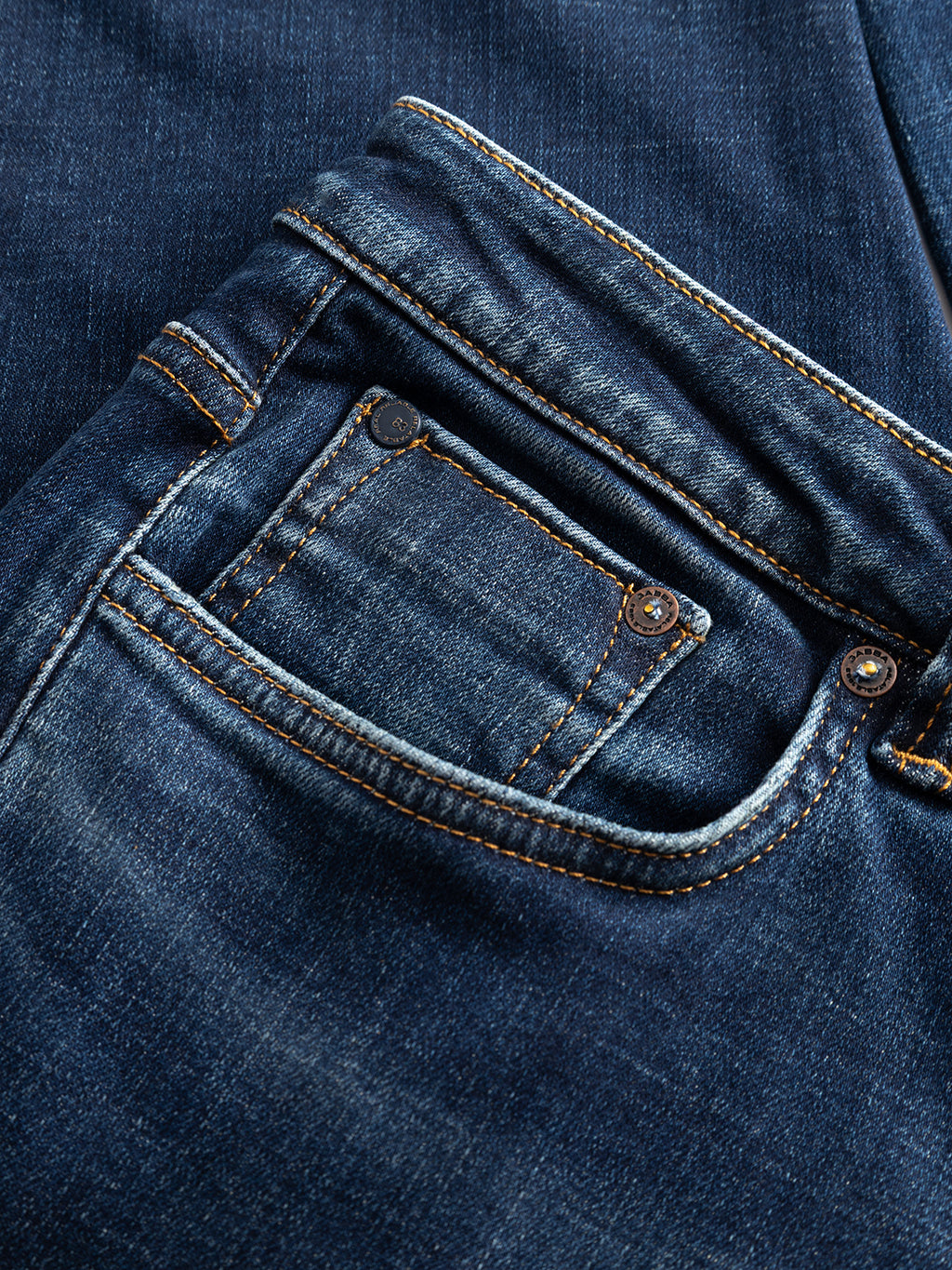 Close-up of the front pocket and coin pocket of Gabba GABjones Bekham DS0002 Jeans in dark blue denim, featuring visible orange stitching and metal rivets, crafted from comfort stretch material in a worn mid-blue wash.