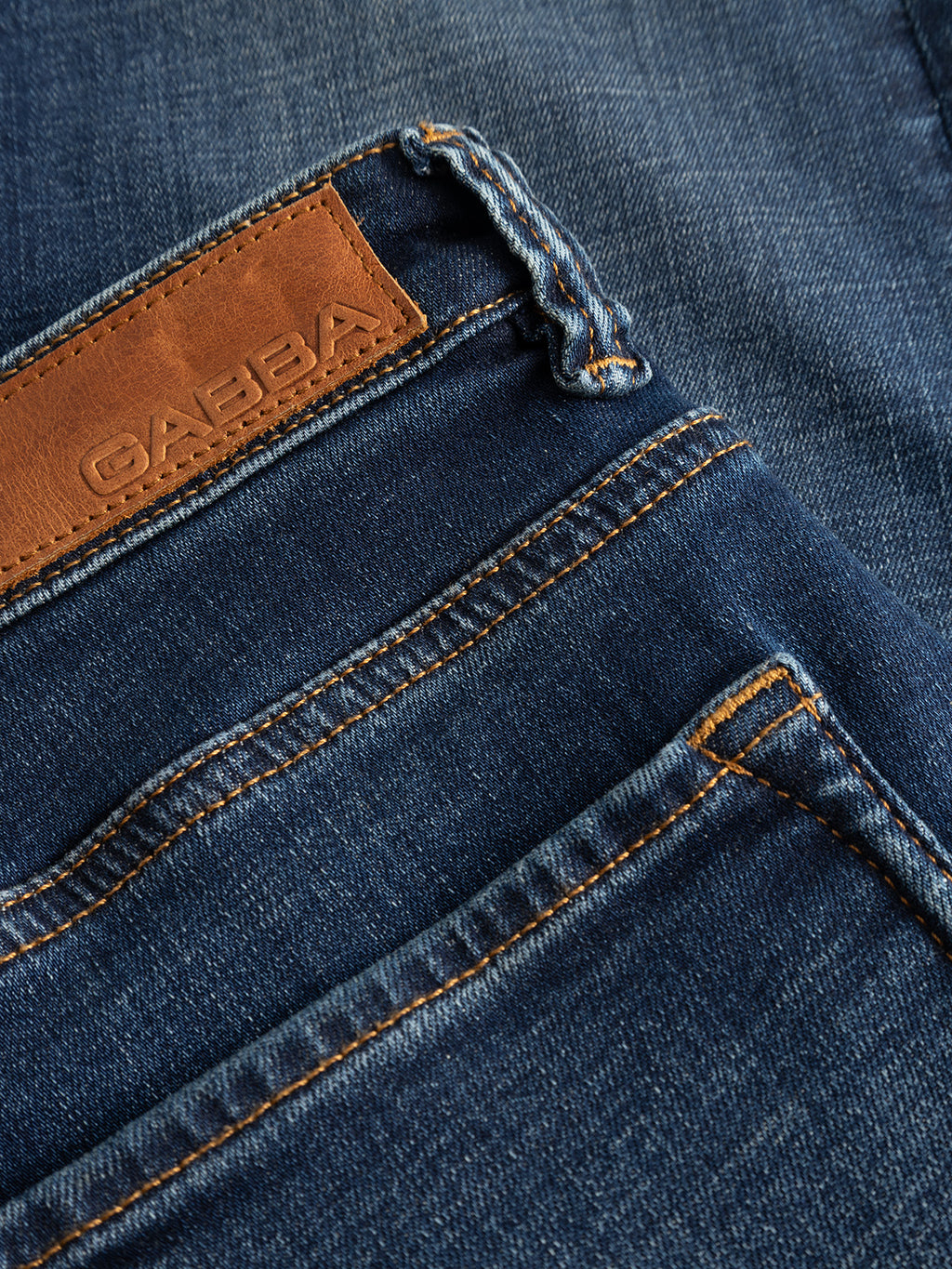 Close-up of GABjones Bekham DS0002 Jeans by Gabba in dark blue denim, highlighting the brown leather patch with partial Gabba branding, detailed stitching, and front pocket. Crafted from comfort stretch denim in a slim straight fit, these jeans are perfect for everyday ease.