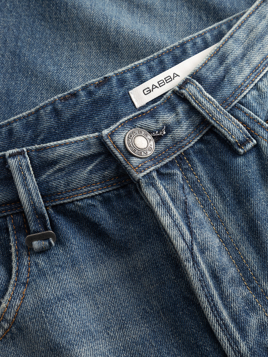 Close-up of dark blue GABsenna Wolv DS0004 denim jeans by Gabba, featuring an open hand pocket design, metallic button, belt loops, and a white Gabba label sewn inside the waistband.