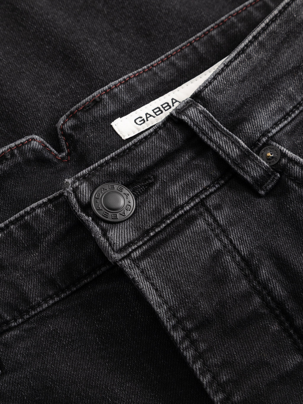 Close-up of the high-density black denim on the GABalex Cropped Blerb WW0031 Jeans by Gabba, featuring a sturdy waistband with a metal button and belt loop. Inside the waistband, a white label reads ‘Gabba,’ accentuating the washed black finish.