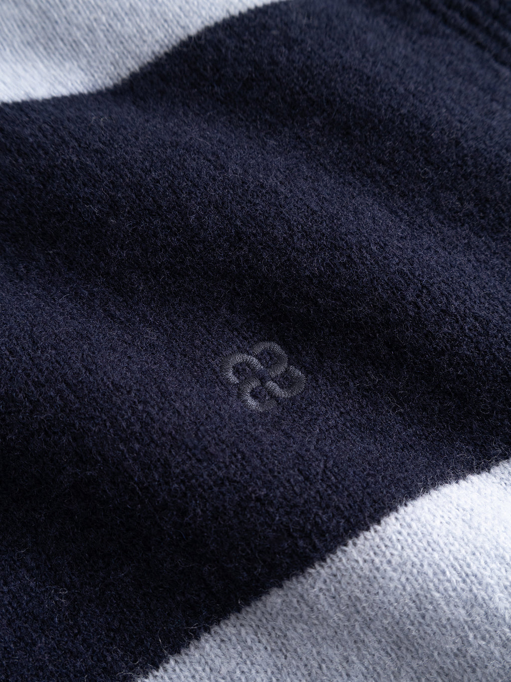 A close-up of the Gabba GABworren Polo Stripes Aico LS Knit in Navy Stripe, this men’s regular fit pullover features soft, dark blue and light gray stripes with a discreet embroidered logo at the center, highlighting the refined details of this sweater.
