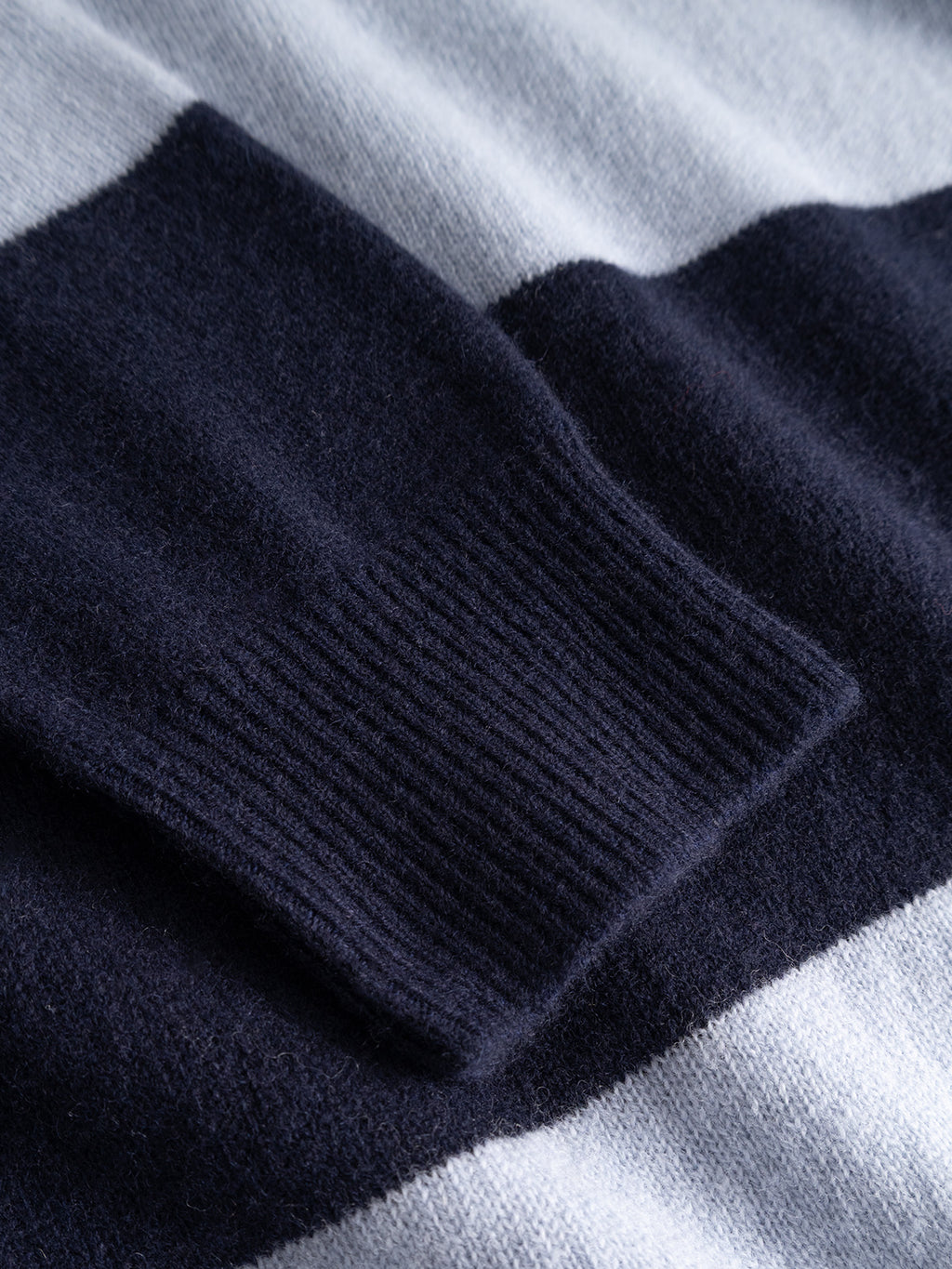 Close-up of the GABworren Polo Stripes Aico LS Knit - Navy Stripe by Gabba, featuring navy blue and light gray horizontal stripes, with a detailed view of its ribbed navy cuff on this men’s regular fit pullover.