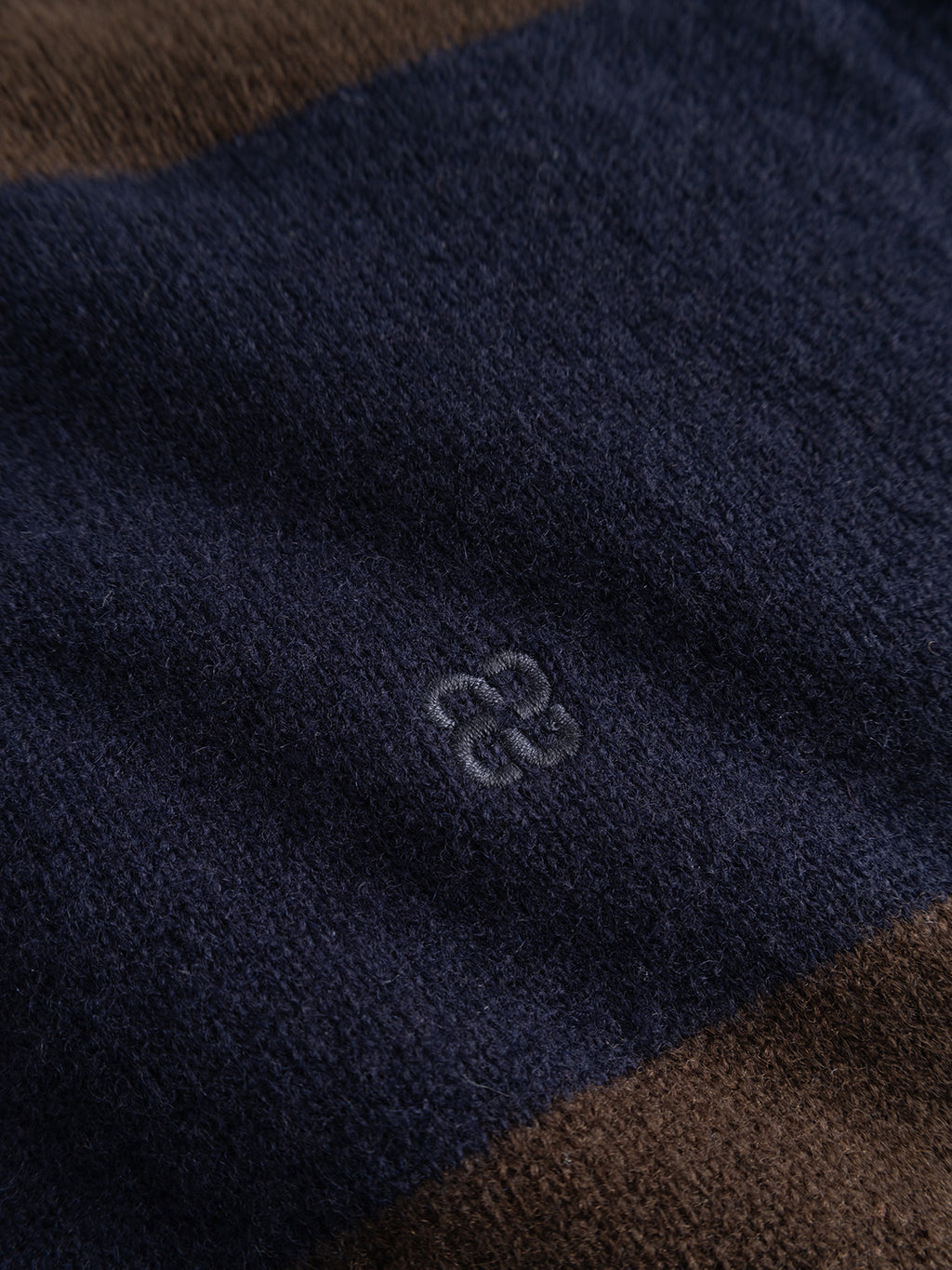 Close-up of the Gabba GABworren Polo Stripes Aico LS Knit in Brown Stripe, featuring navy and brown stripes with a small light blue embroidered knot detail at the center. This soft wool polo showcases a notably plush, fuzzy texture.