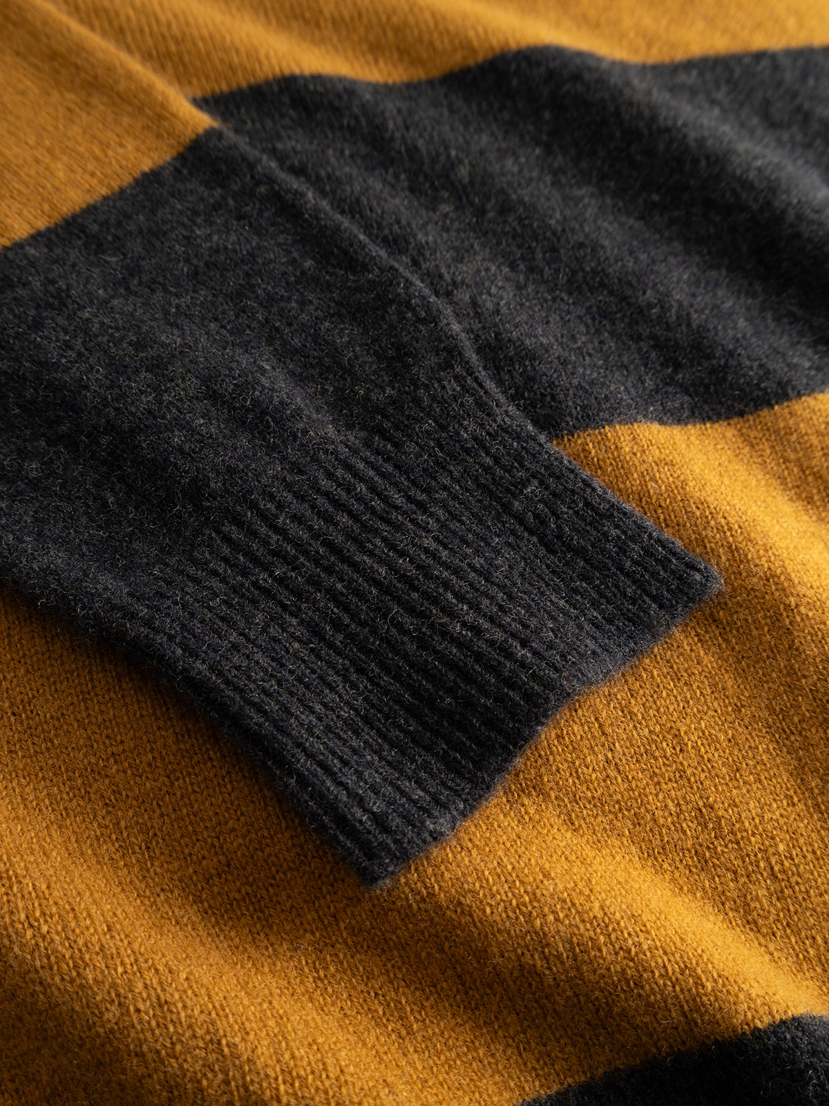 Close-up of Gabba’s GABworren Polo Stripes Aico LS Knit in yellow stripes, highlighting the wide horizontal mustard yellow and dark gray stripes. The image showcases the textured knit fabric and detailed stitching of this men’s regular fit sweater.