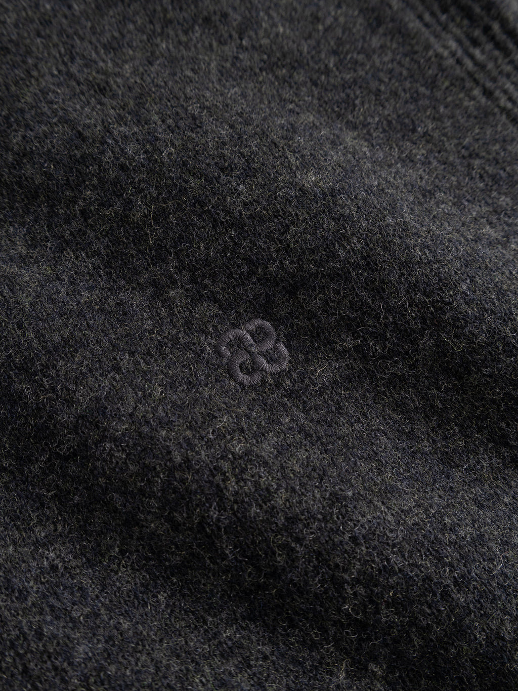 Close-up of the Gabba GABworren Polo Aico LS Knit in Dark Grey Mel—a men’s regular fit sweater crafted from soft, slightly fuzzy wool knit. It features a ribbed polo collar for refined detailing and a small, subtle embroidered logo with two interlocking shapes at the center.