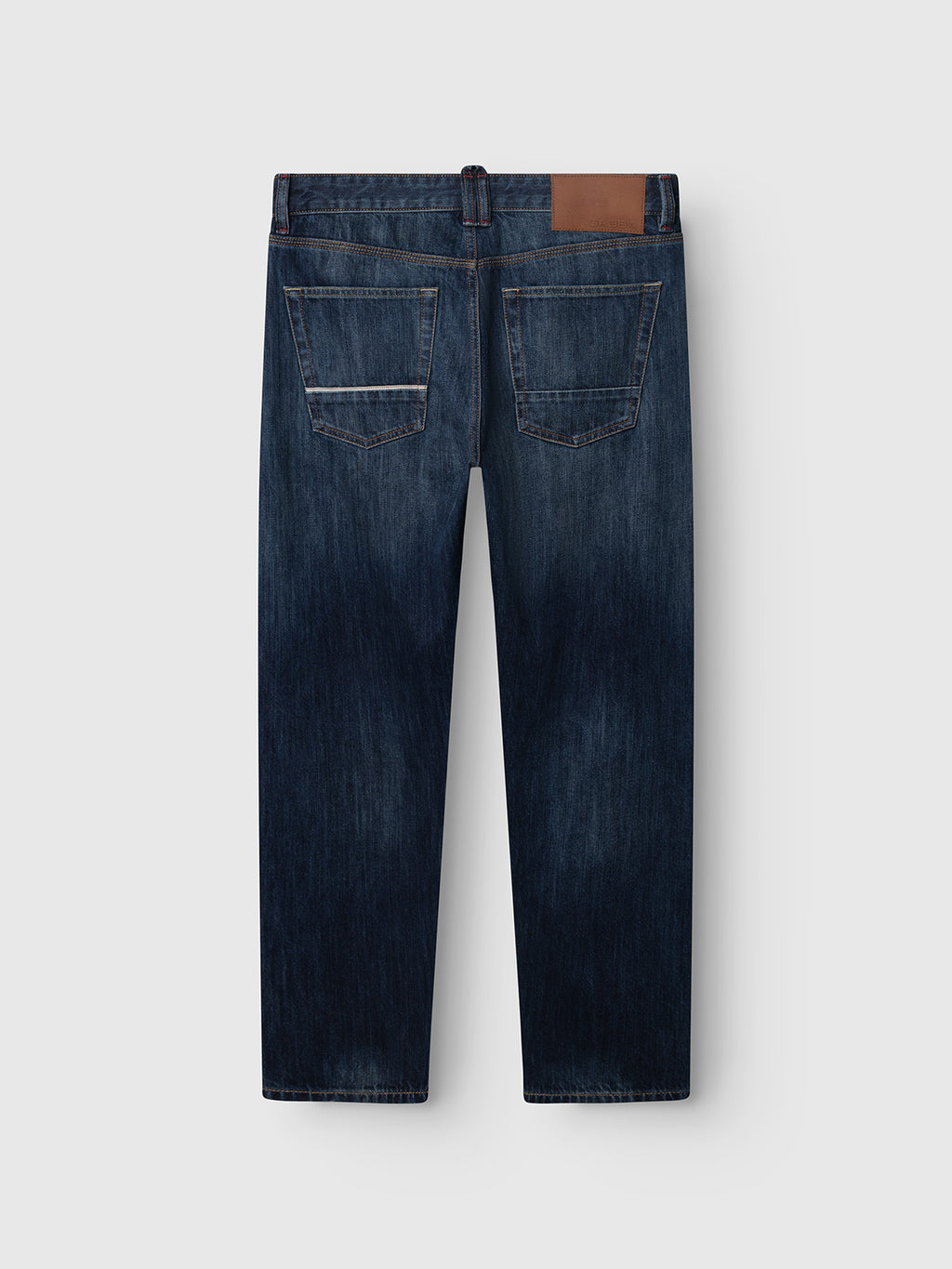 Gabba GABcarl Selvedge DS0005 Jeans in dark blue denim, shown from the back, feature two rear pockets with distinctive stitching and a brown leather patch on the waistband. Made from recycled cotton selvedge denim by Candiani, these jeans offer a loose tapered fit with a straight leg cut.