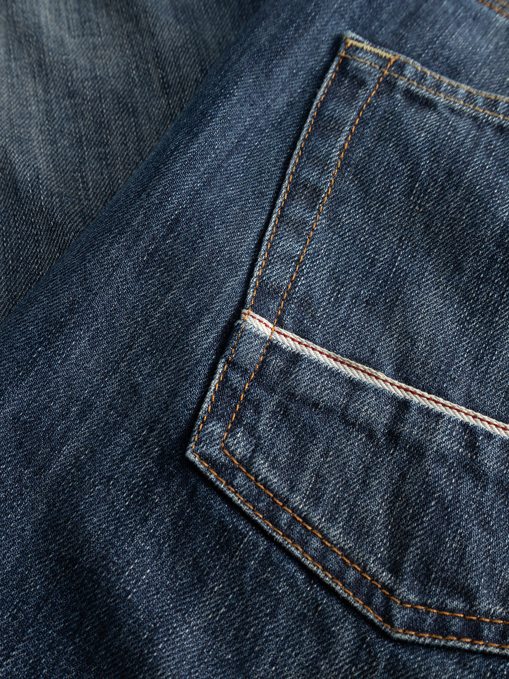 Close-up of the Gabba GABcarl Selvedge DS0005 Jeans in dark blue denim, featuring a back pocket with visible orange stitching and a faded texture, crafted from recycled cotton selvedge denim.
