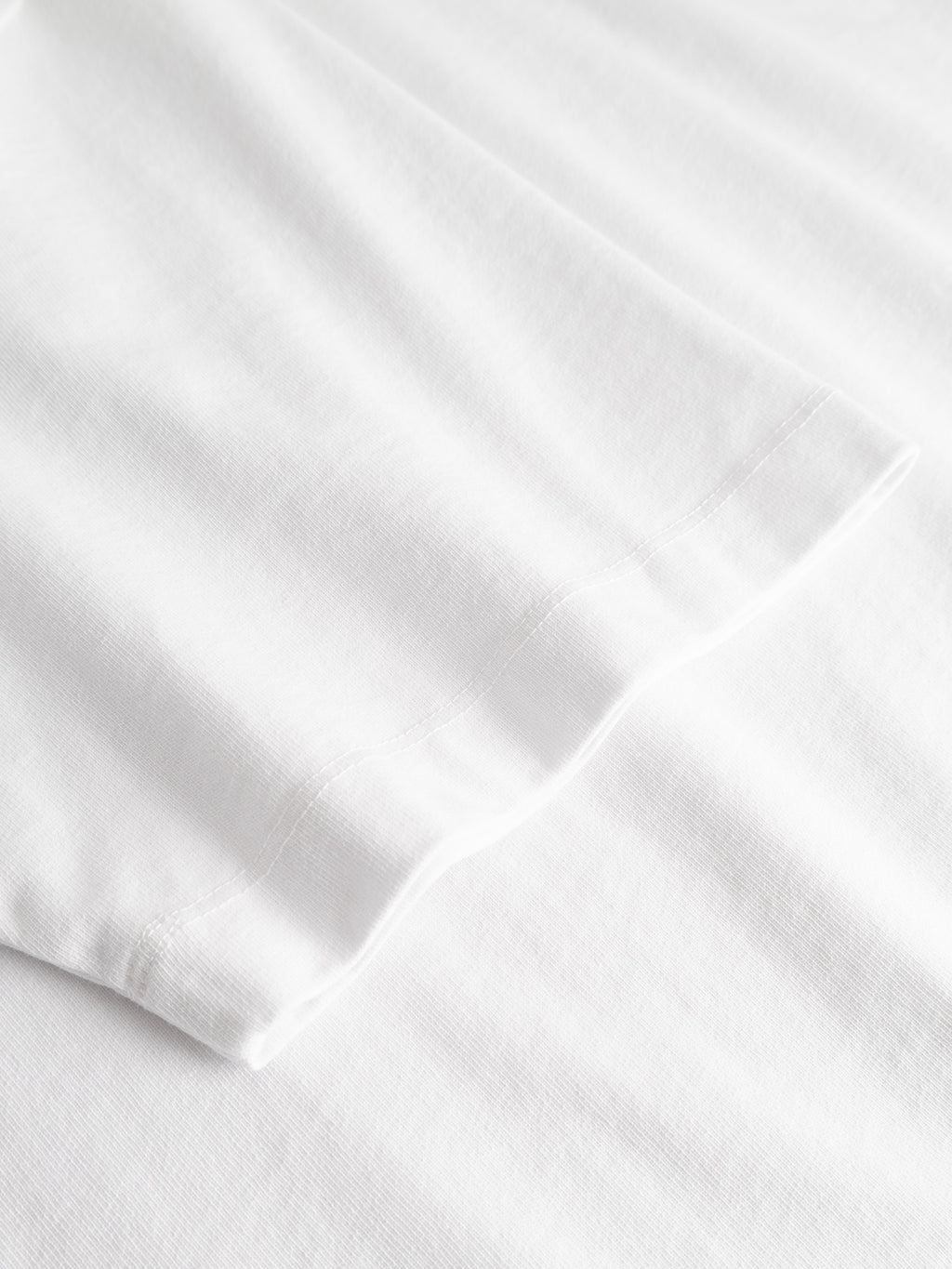 Close-up view of the Gabba GABnigel Wix Pkt Boxy Hour SS T-Shirt in white, showing the boxy sleeve lying flat on a white surface and highlighting the heavyweight cotton fabric texture and seam details.