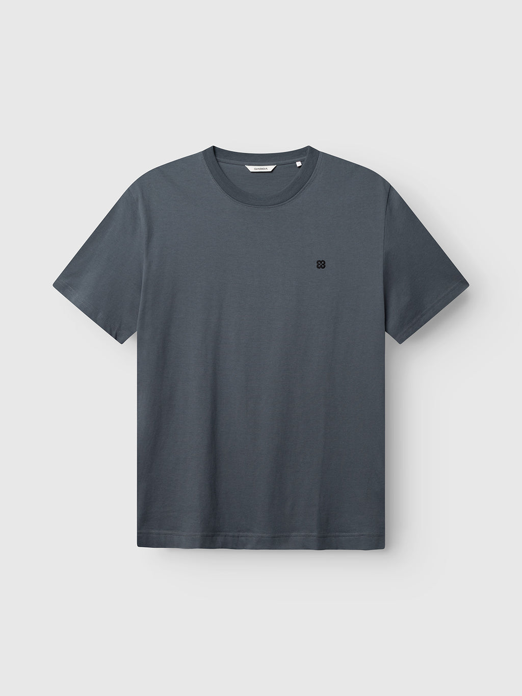 A GABdune Element GOTS SS T-Shirt by Gabba in Turbulence Blue, made from organic cotton with short sleeves and a small black embroidered logo on the left chest, displayed on a light gray background.