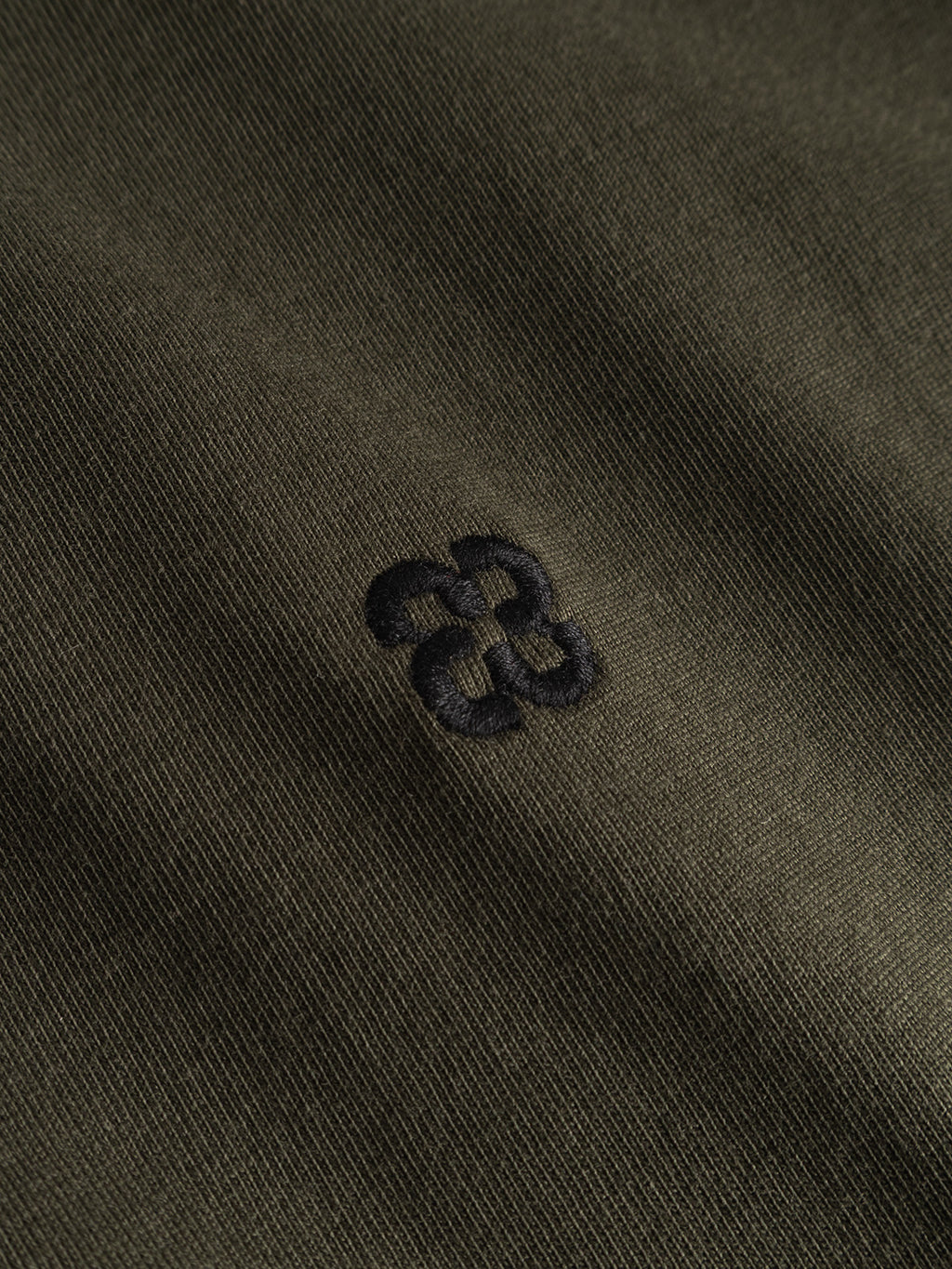 Close-up of the Gabba GABdune Element GOTS SS T-Shirt in Forest Night, crafted from fine-textured, GOTS-certified organic cotton. Features a small embroidered black geometric logo at the center.