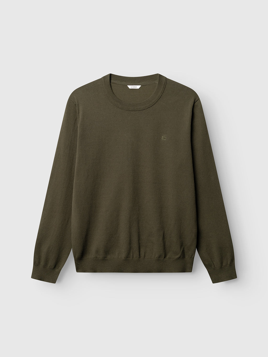 The Gabba GABfumo Element Spy LS Knit in Forest Night is a plain, long-sleeve, crew neck sweater made from soft flat-knit cotton, shown laid flat on a light gray background. This regular fit design features a small, subtle embroidered logo on the left chest.