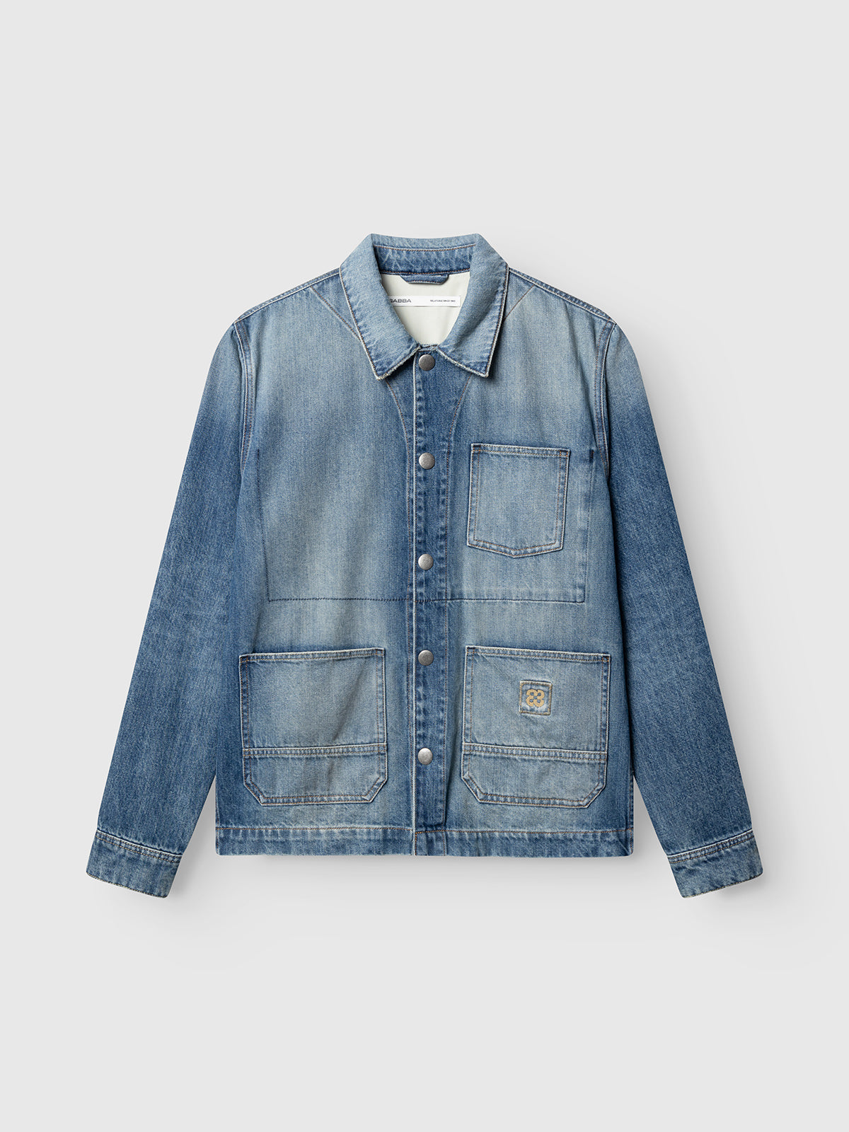 The Gabba GABbeta Wolv DS0004 LS Overshirt is a dark blue denim layer featuring a collar, metal buttons, and three spacious front pockets—including one on the chest. Inspired by classic workwear and finished with a subtle laser-washed effect, this overshirt is photographed laid flat against a plain, light background.