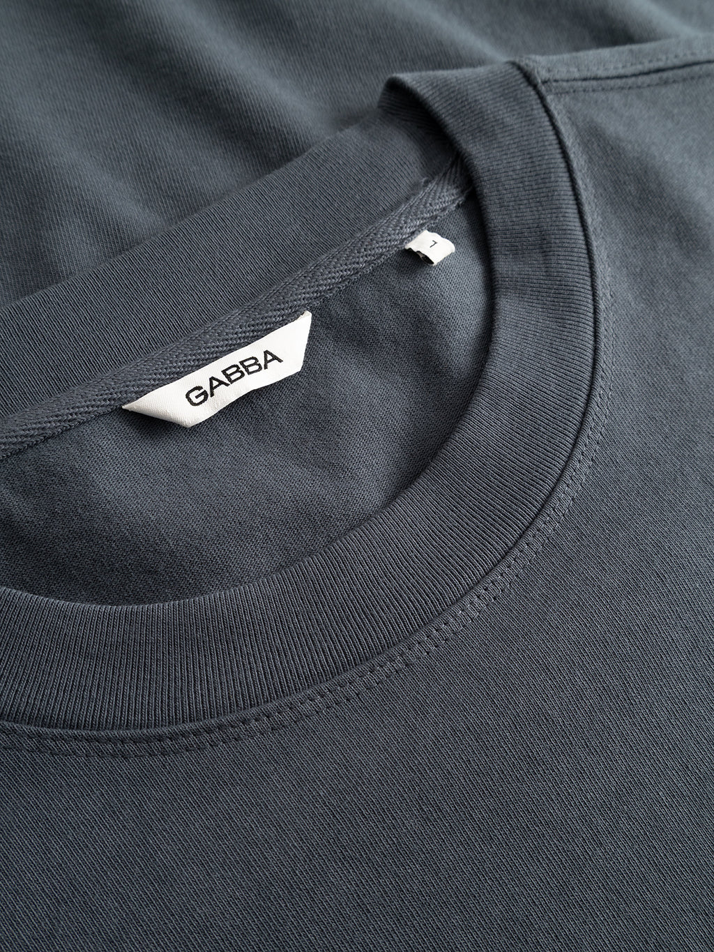Close-up of two neatly folded Gabba GABlegin Wix Chap Boxy Hour SS T-Shirts in Turbulence Blue, stacked together, made from heavyweight cotton with a visible white 