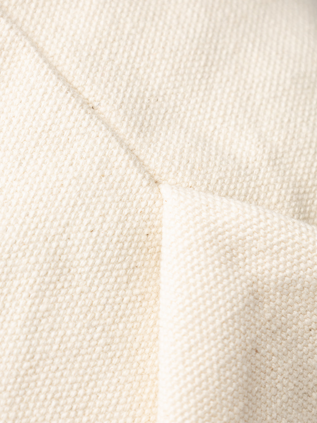 Close-up of the GABchap Tote Bag by Gabba in off-white, showing its textured woven fabric with visible seams and folds that highlight the natural fibers and rugged surface.