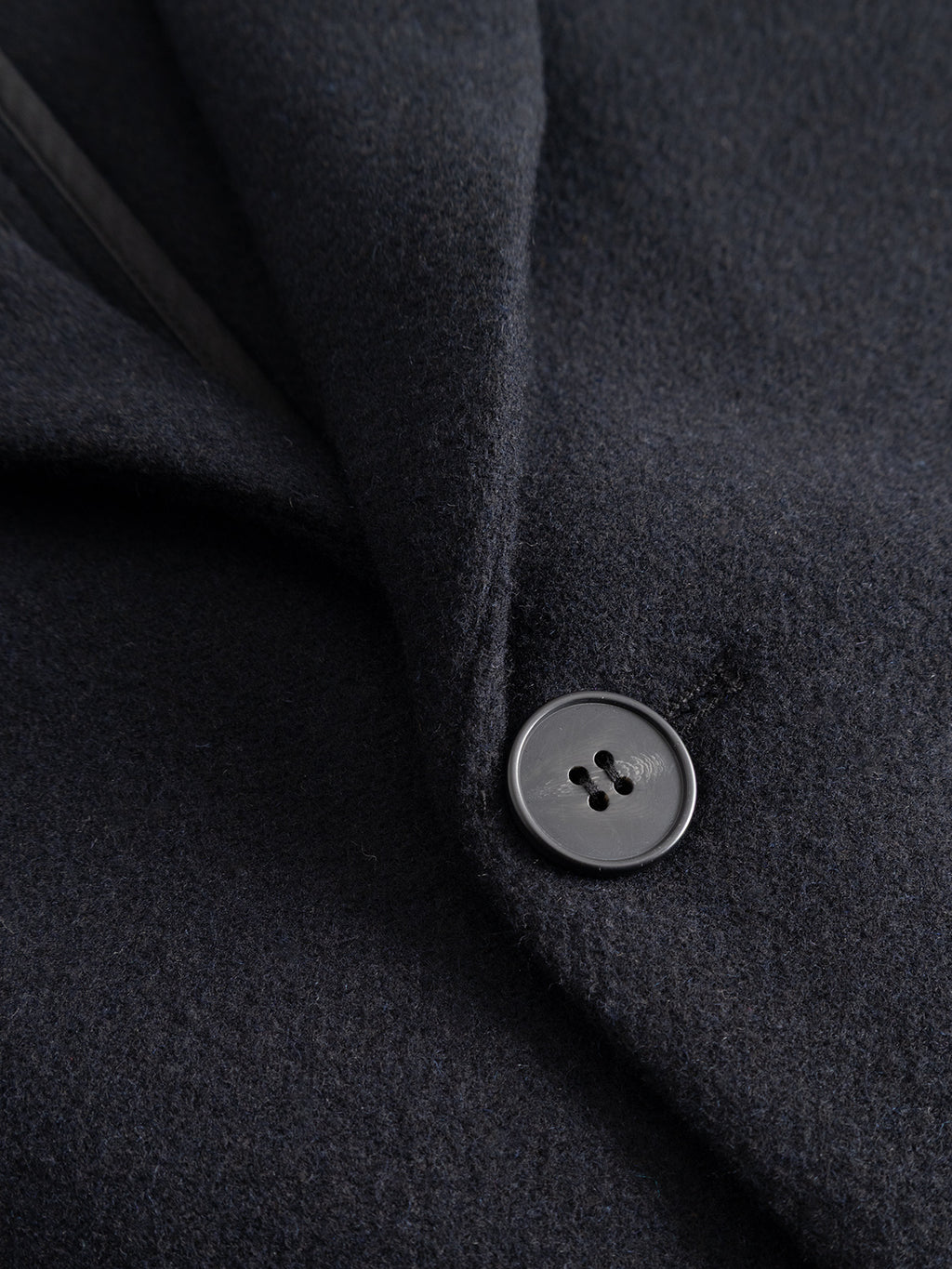 Close-up of the Gabba GABleeds Plain Coat in navy, showcasing a black button and part of the lapel, with detailed emphasis on the texture and stitching of this classic wool-blend outerwear.